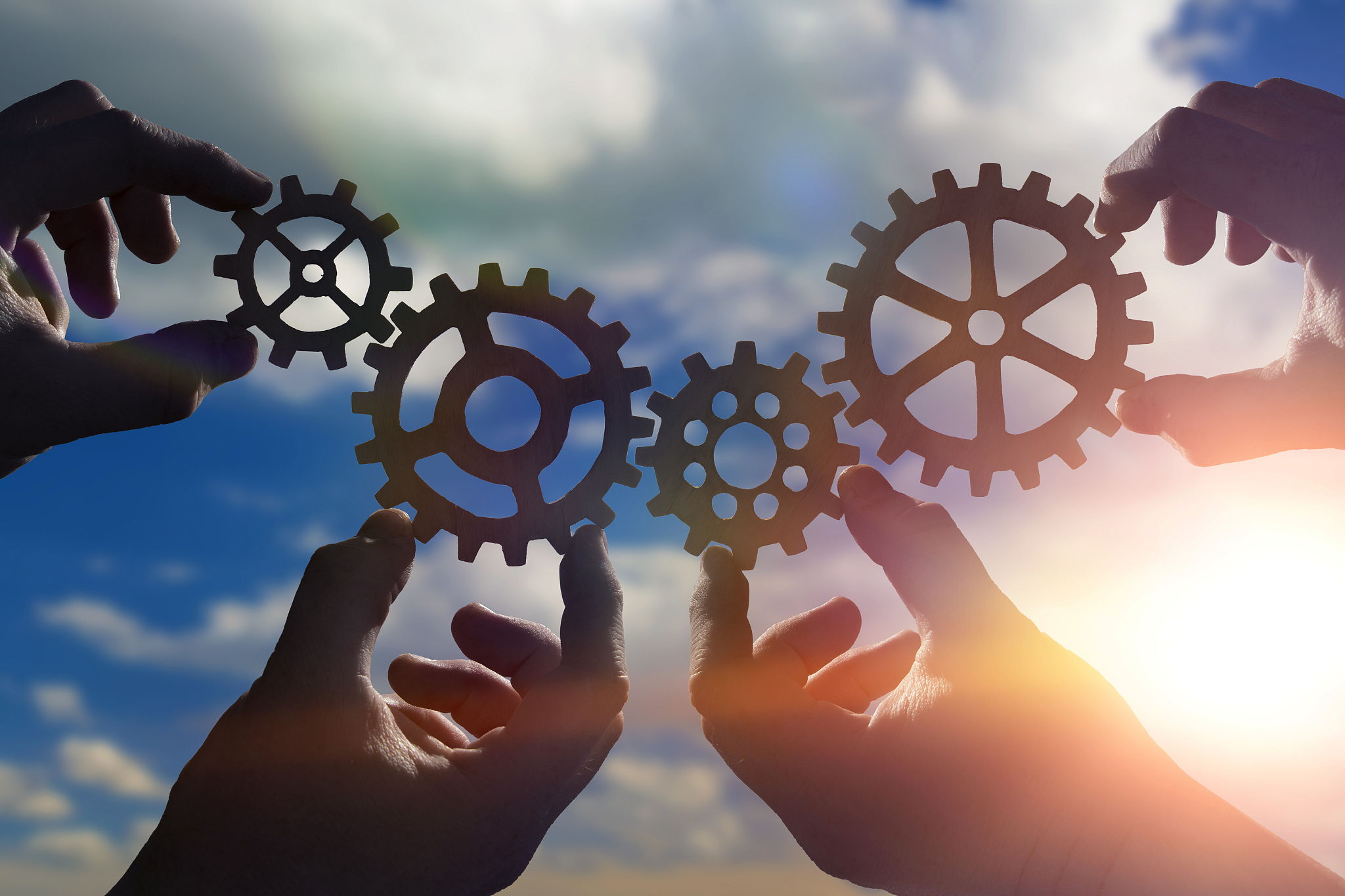 gears in the hands of people against the cloudy sky.