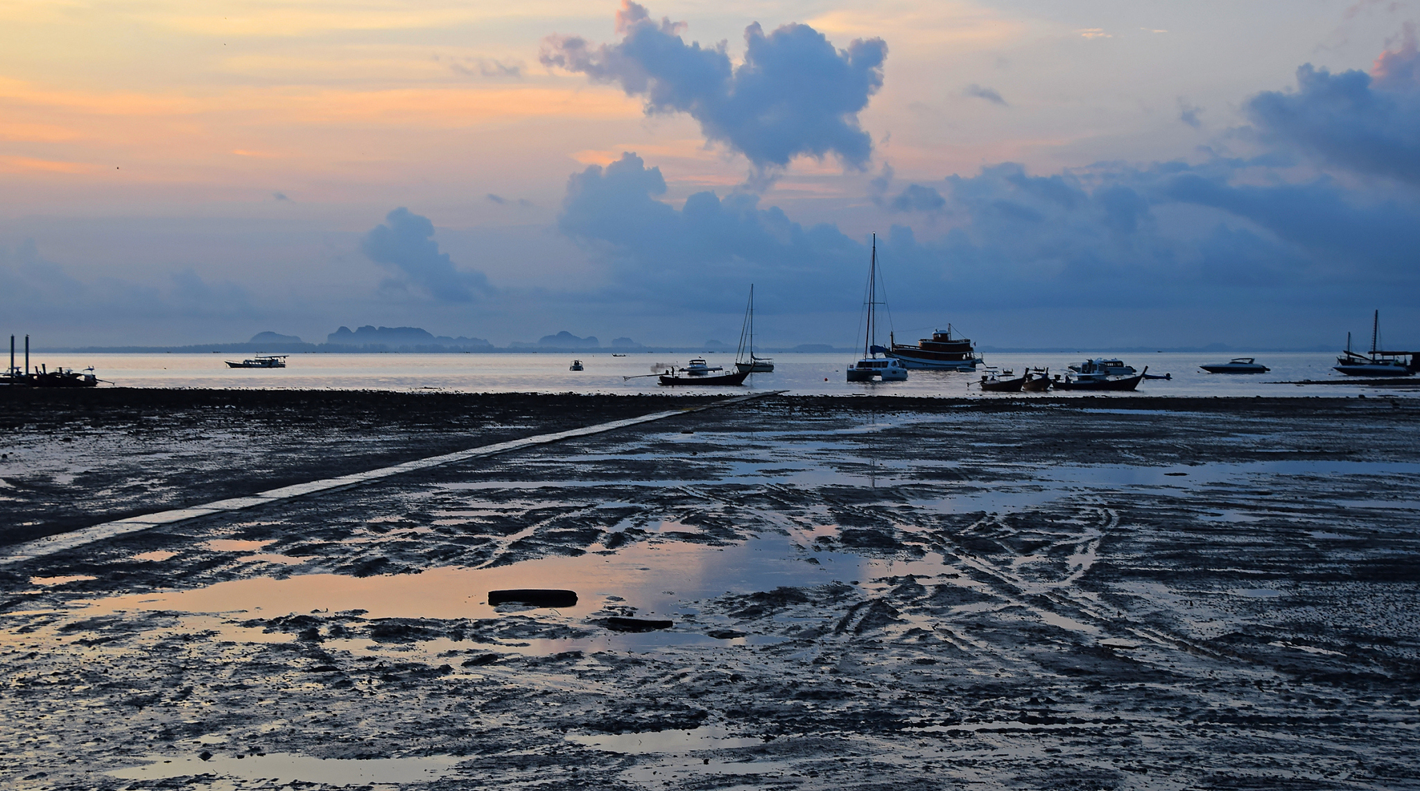 sailboats moored on beach against sky during sunset