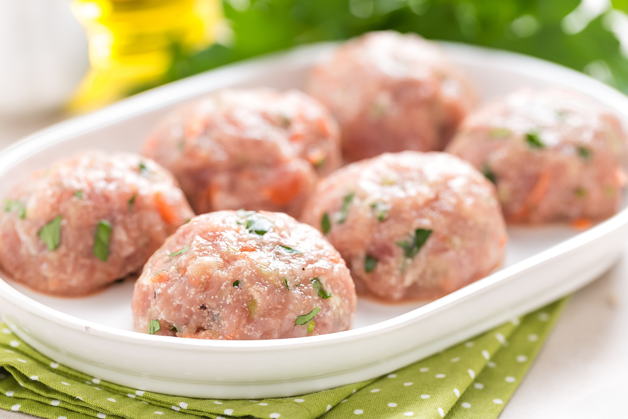 raw meatballs on white plate, cooking in kitchen