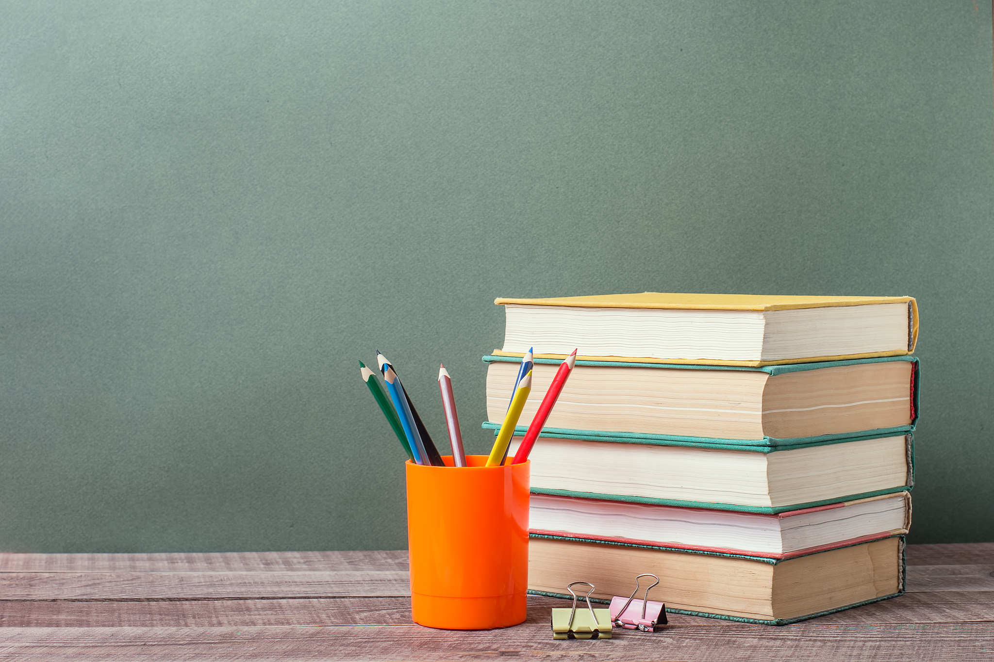 open book, old textbooks, colored pencils on wooden table on pap