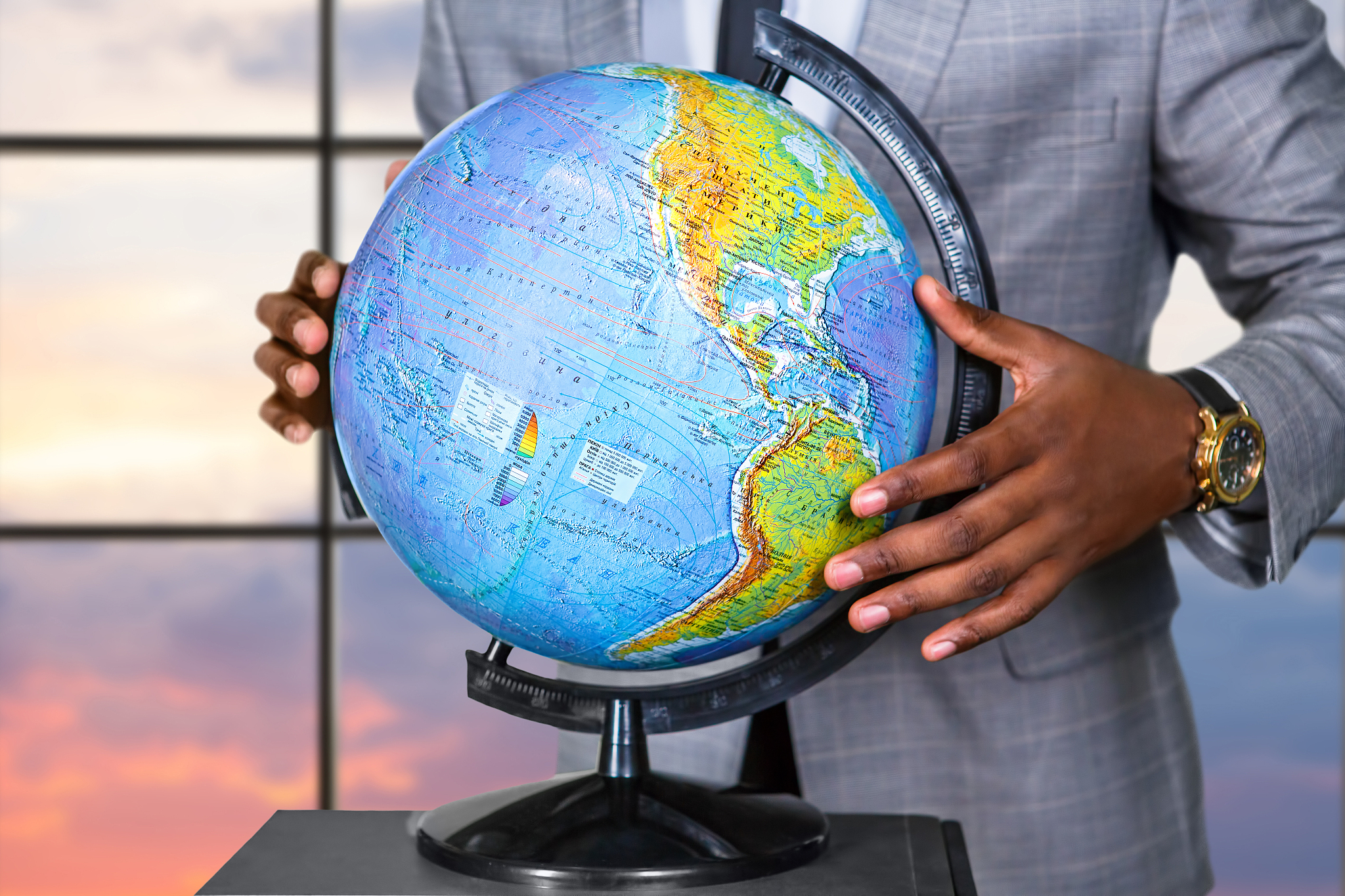 afroamerican holding globe near window.