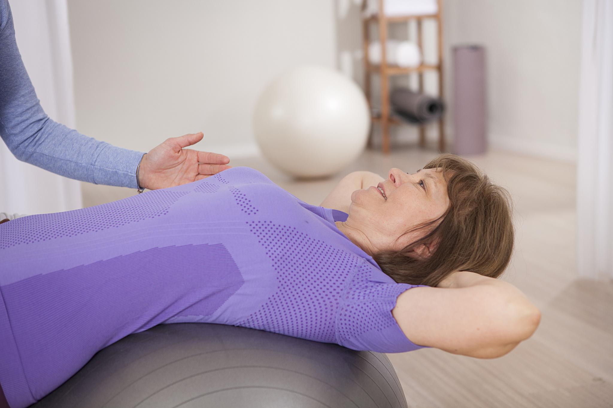 senior woman on exercise ball receiving physiotherapy