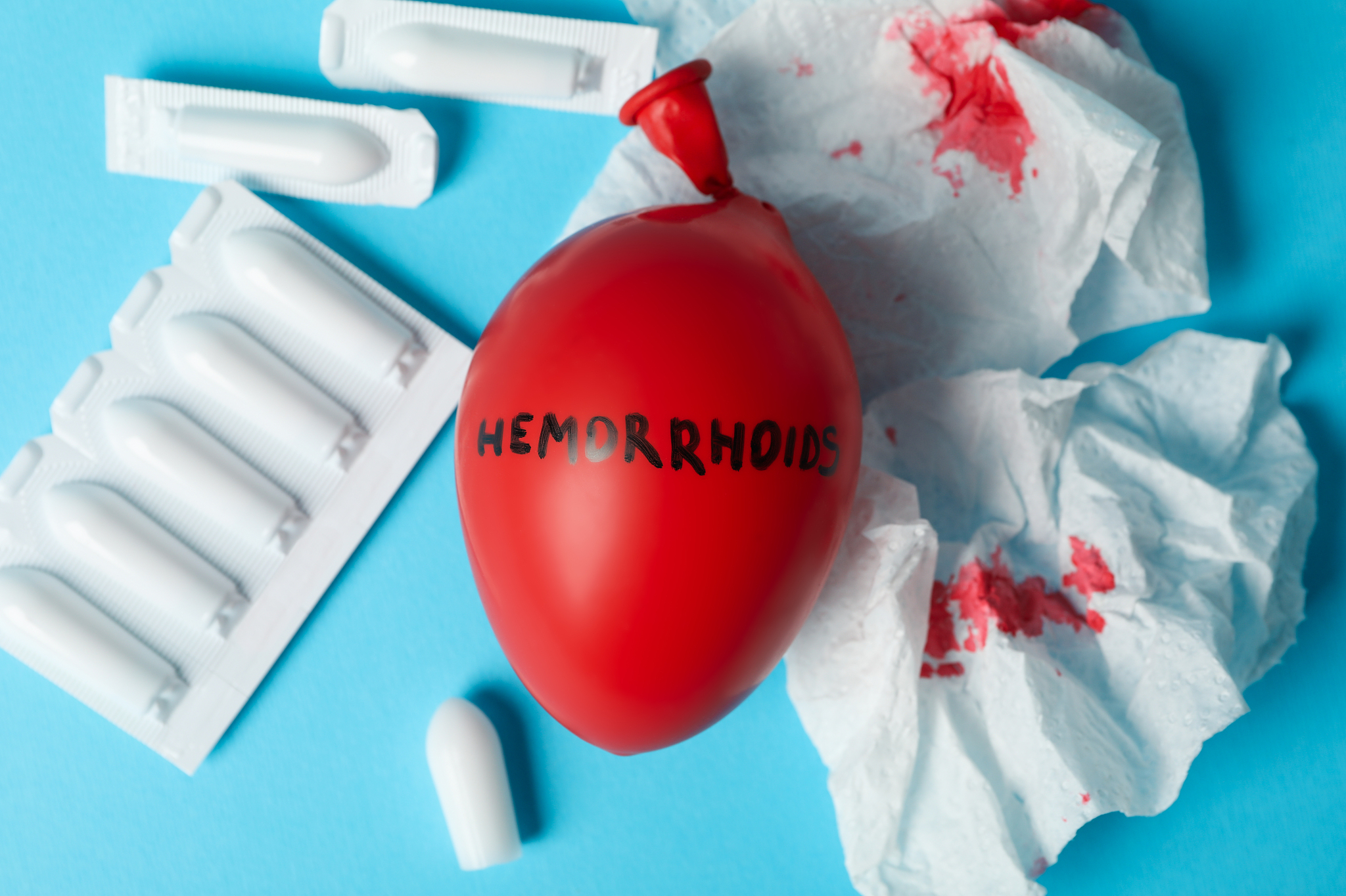 balloon with inscription hemorrhoids, candles and paper with blo