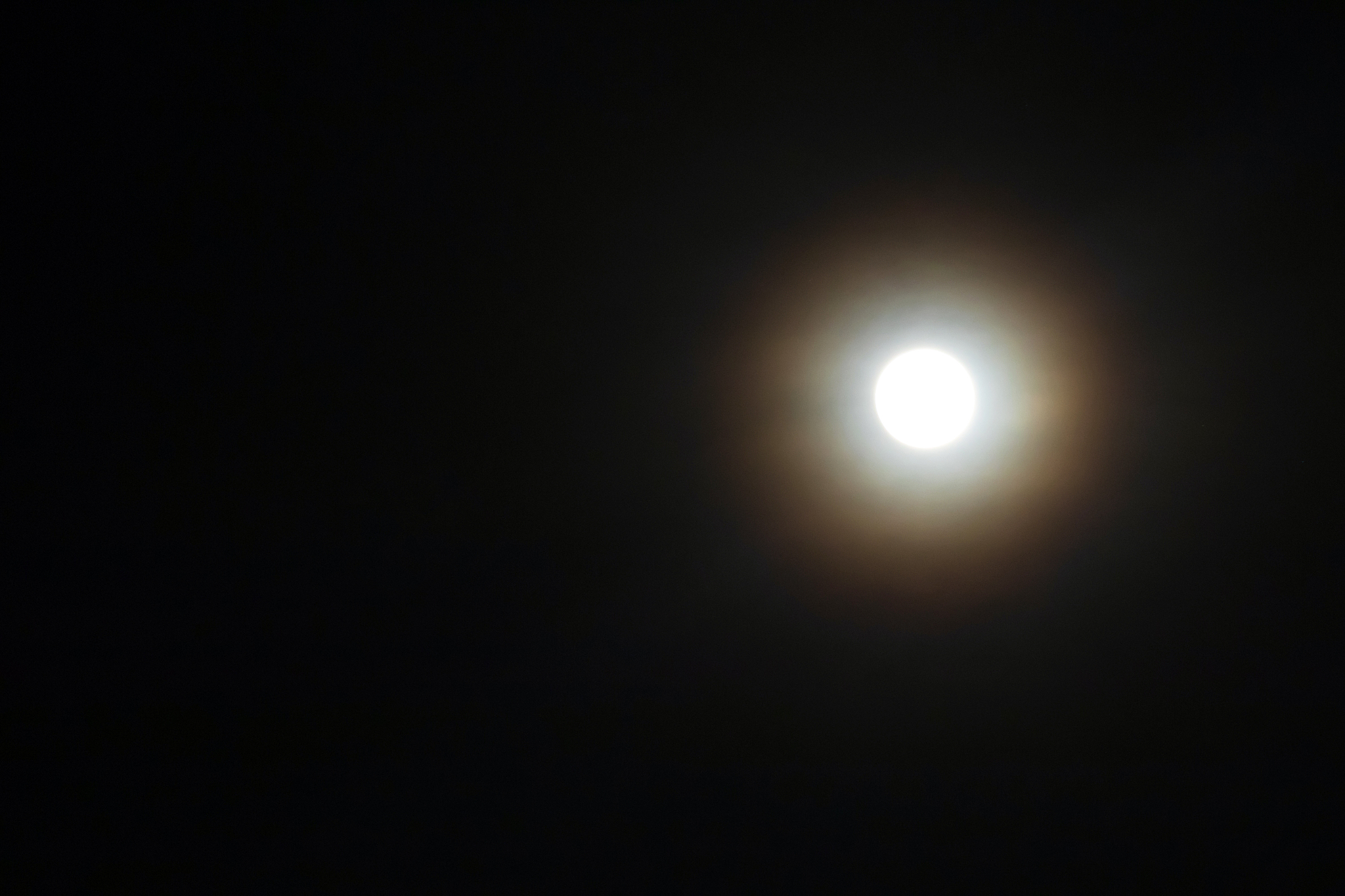 full moon shining glowing light through the darkness of cloudy n