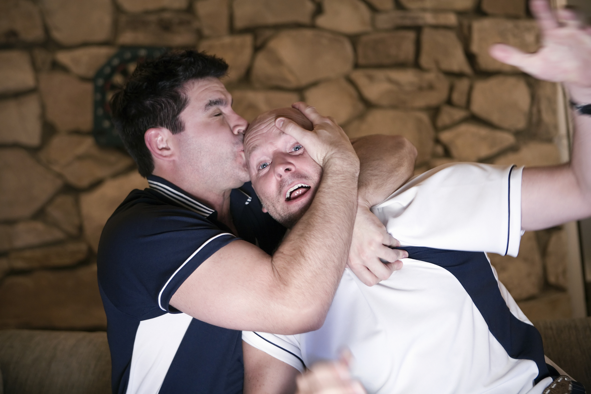 man kissing friend on forehead at home