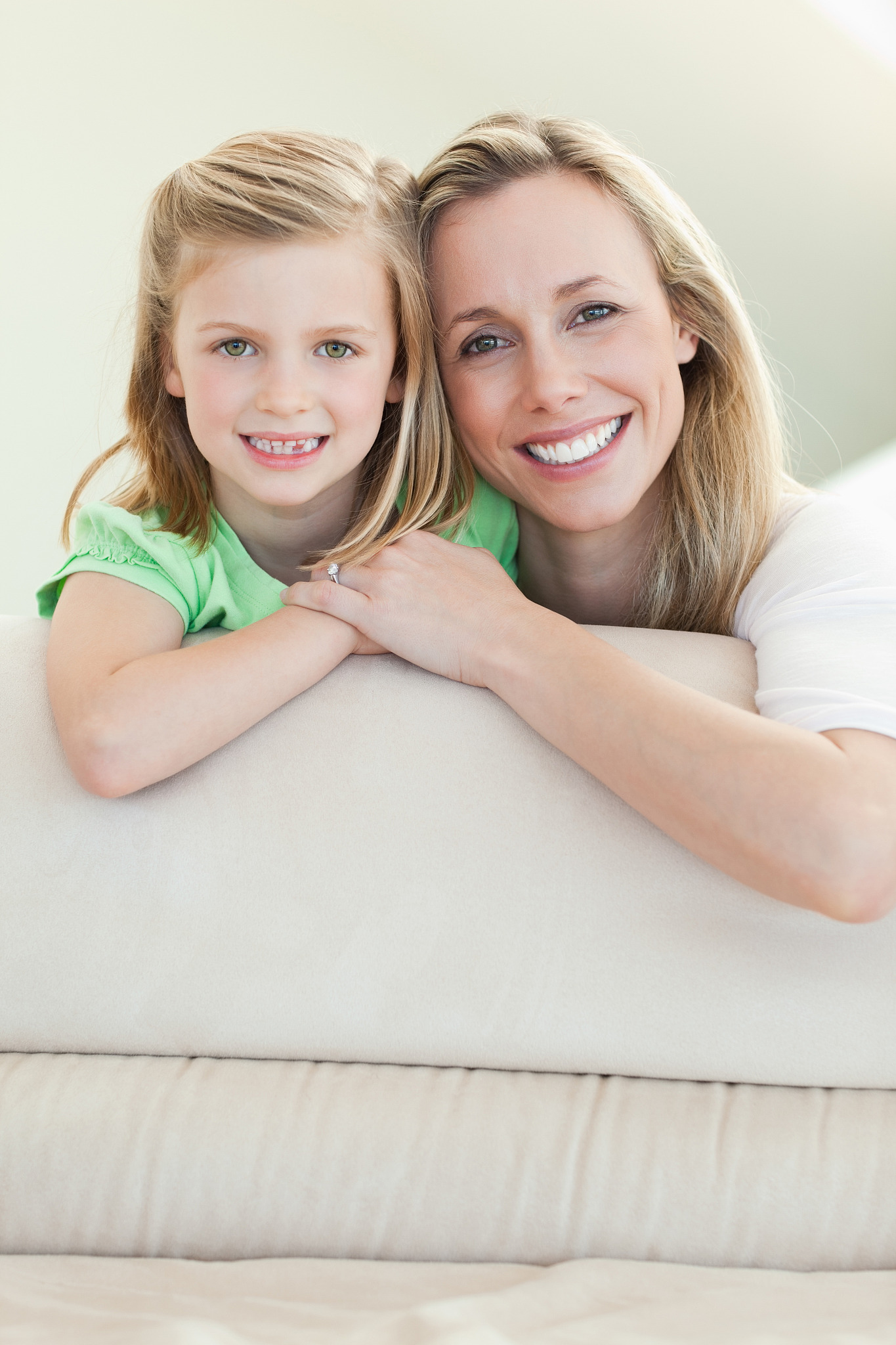 happy smiling mother and daughter together on the sofa