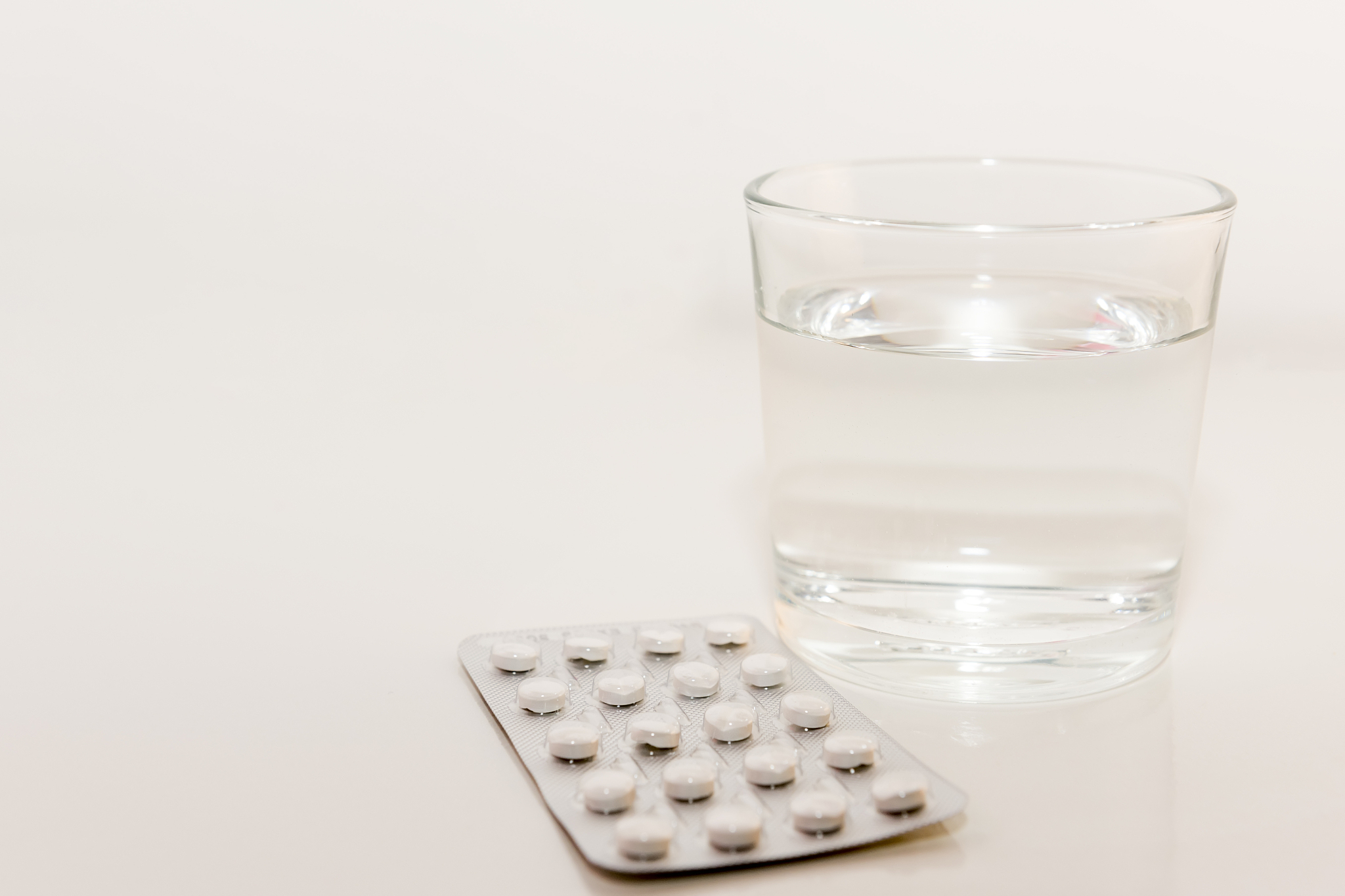 drugs tablet and glass of water on white