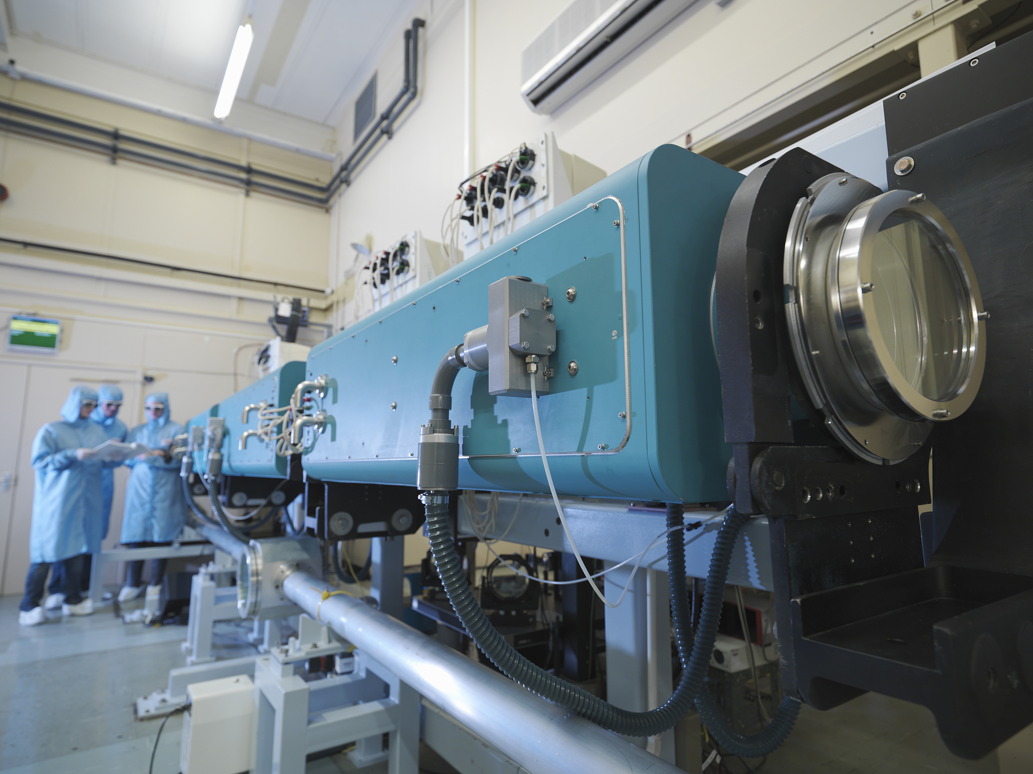 scientists in laboratory, with large laser equipment in foregrou