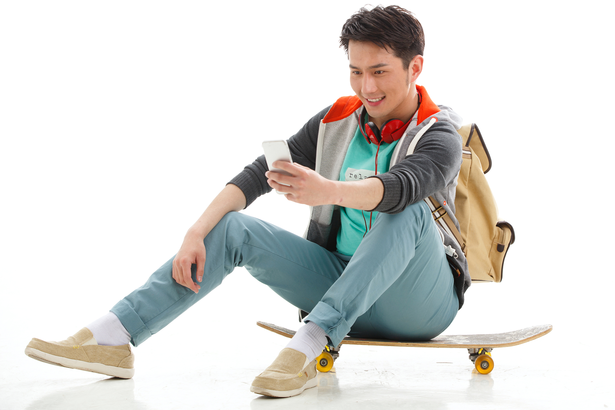 青年男生坐在滑板上玩手机