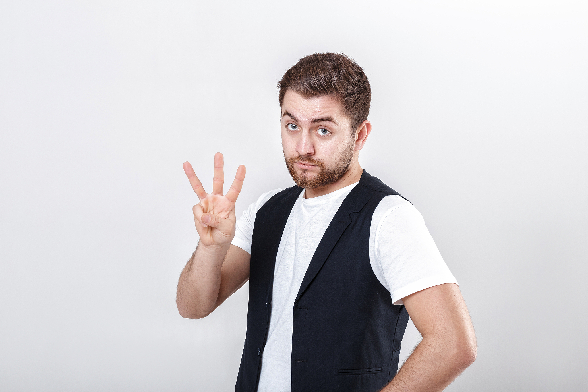 young man with a beard in white shirt and black waistcoat showin