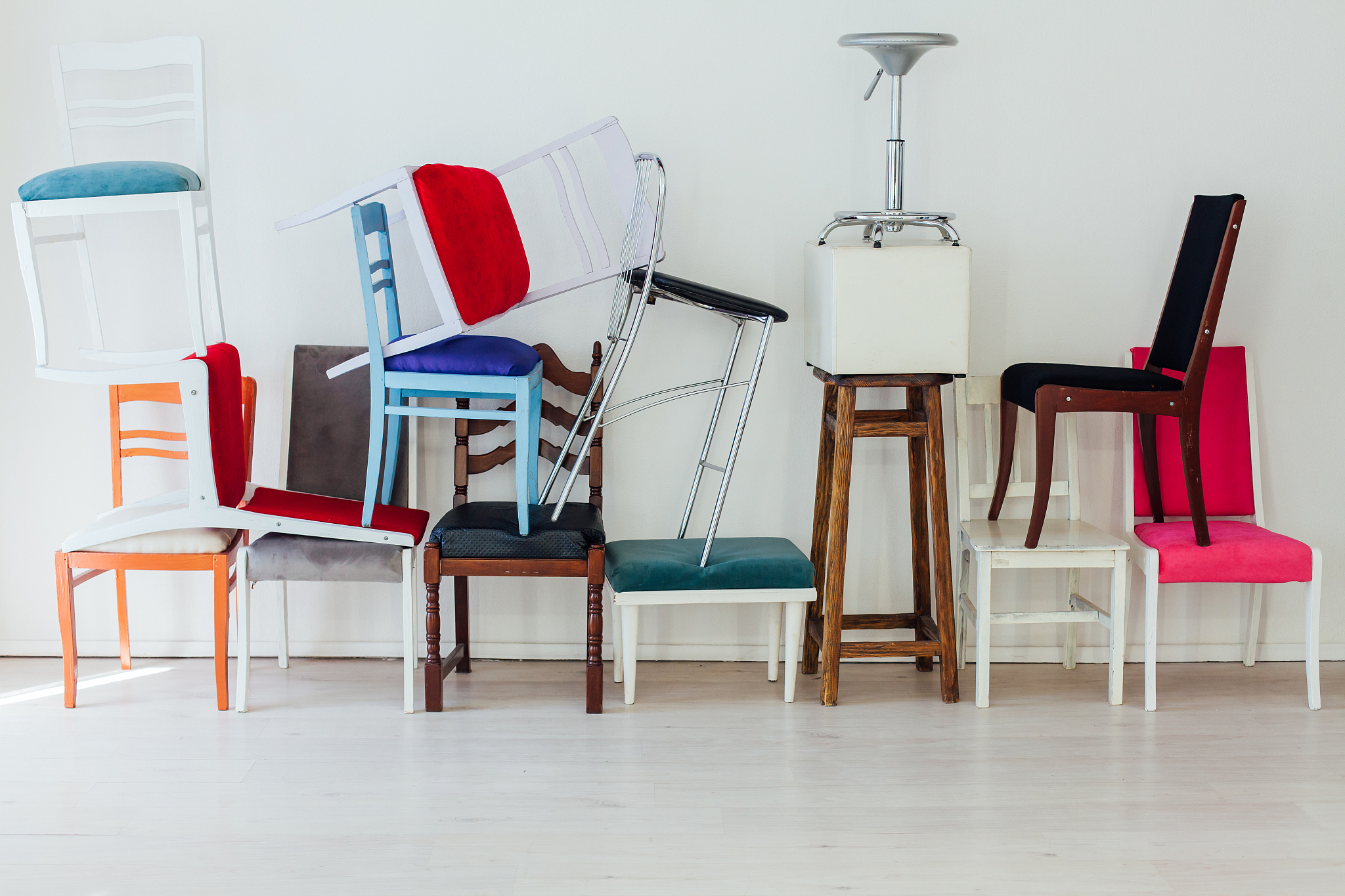 many different chairs stand in the white room