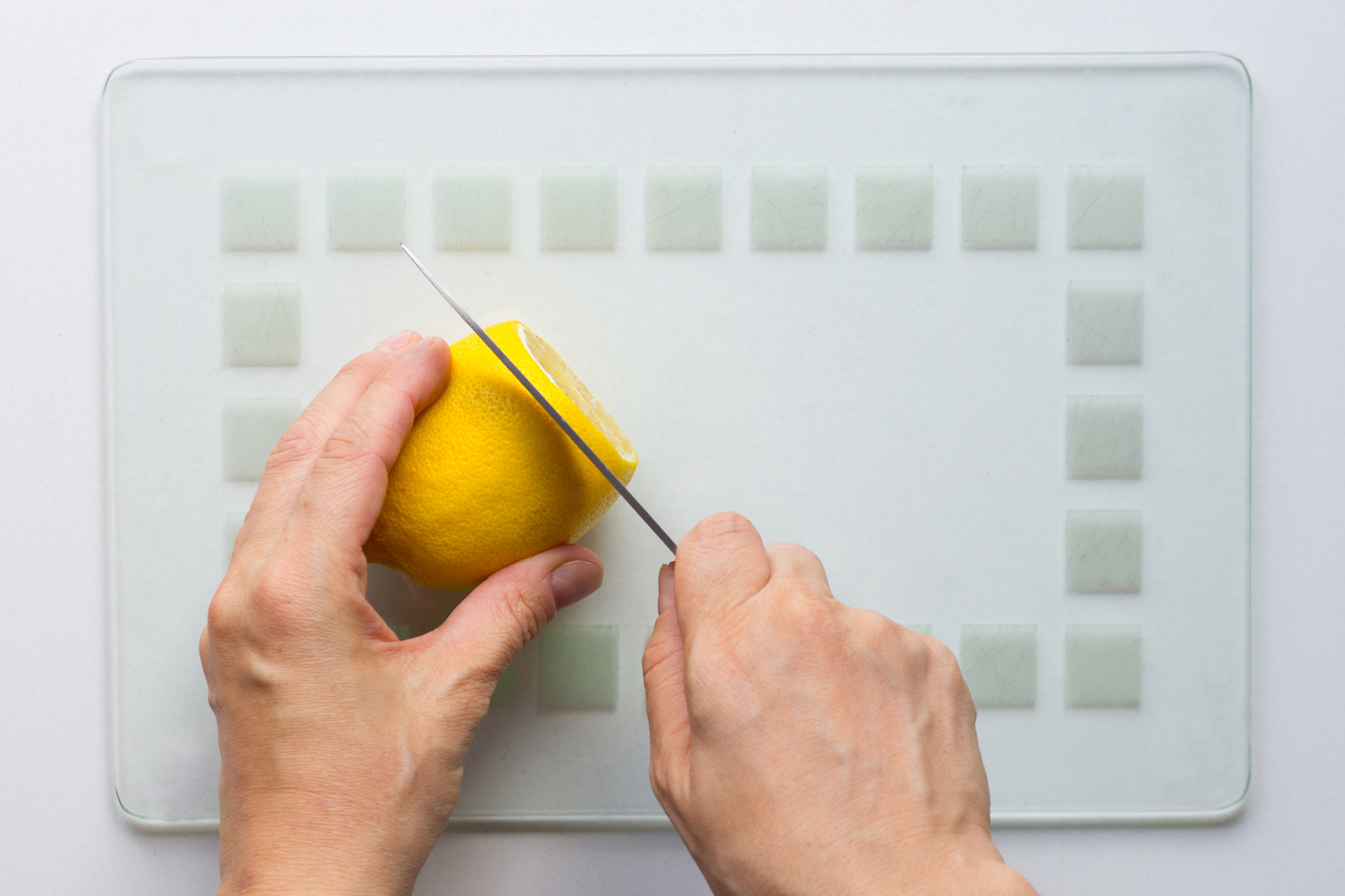 woman hand cut lemon with knife on white background