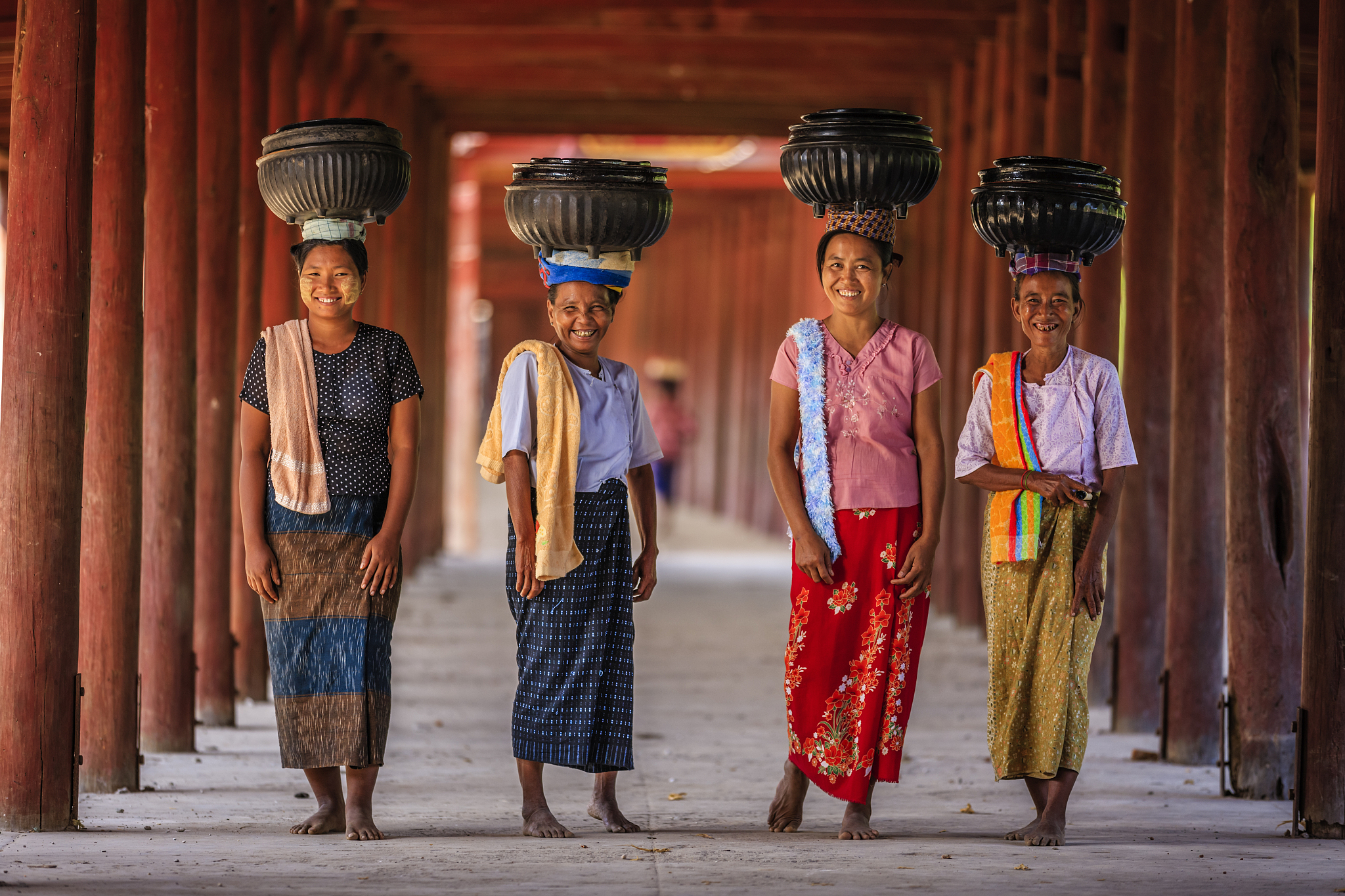 burmese women carrying bowls of rice to the monastery