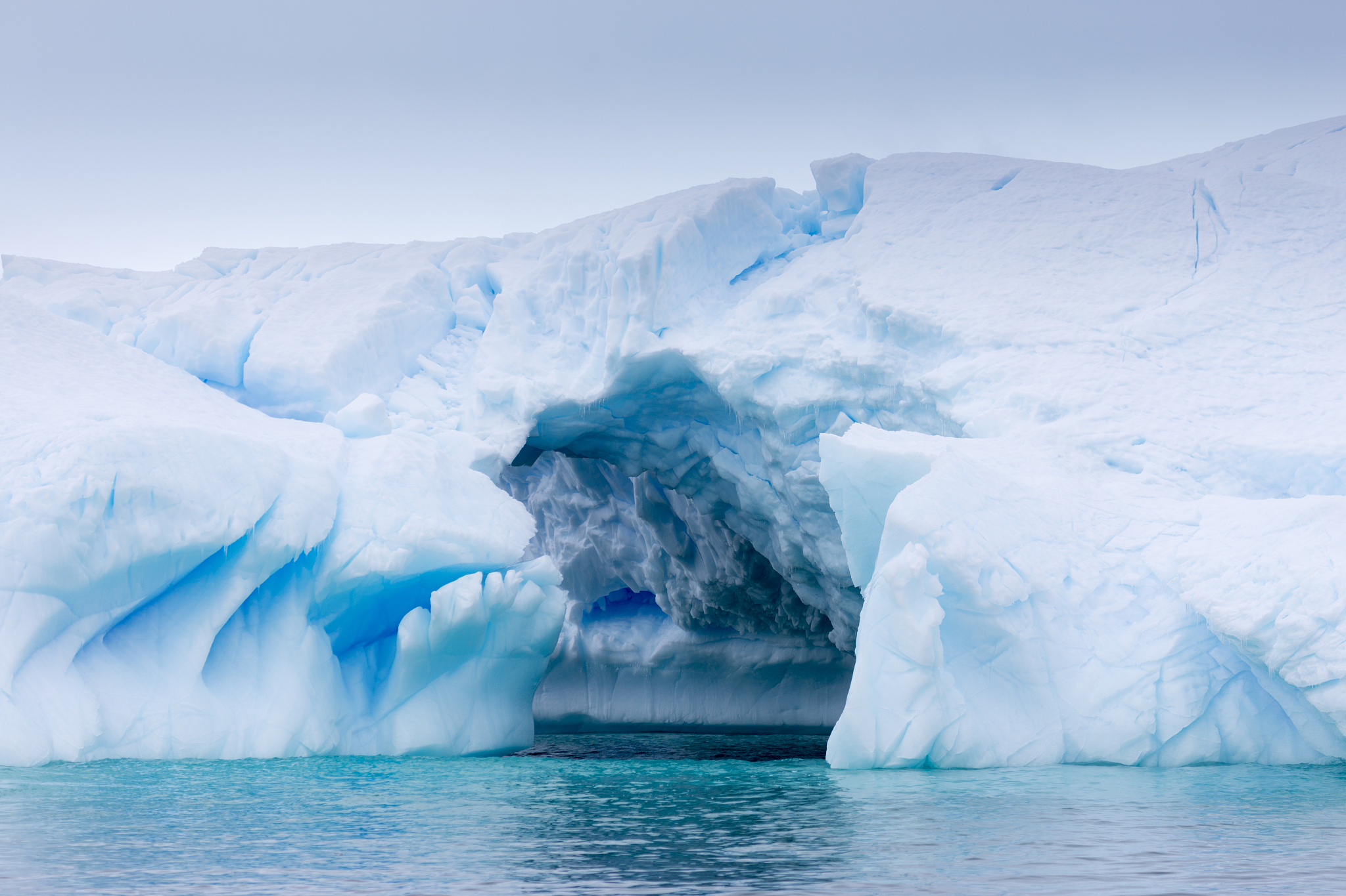 a huge cave has been carved in tho this iceberg.