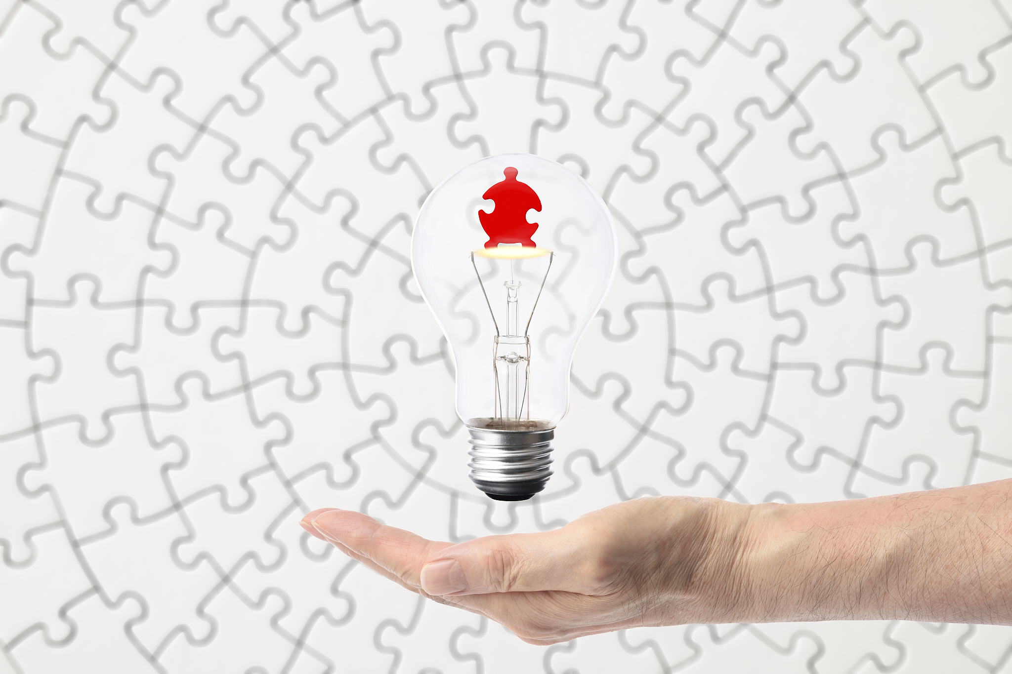 jigsaw puzzle inside the light bulb floating on the hand