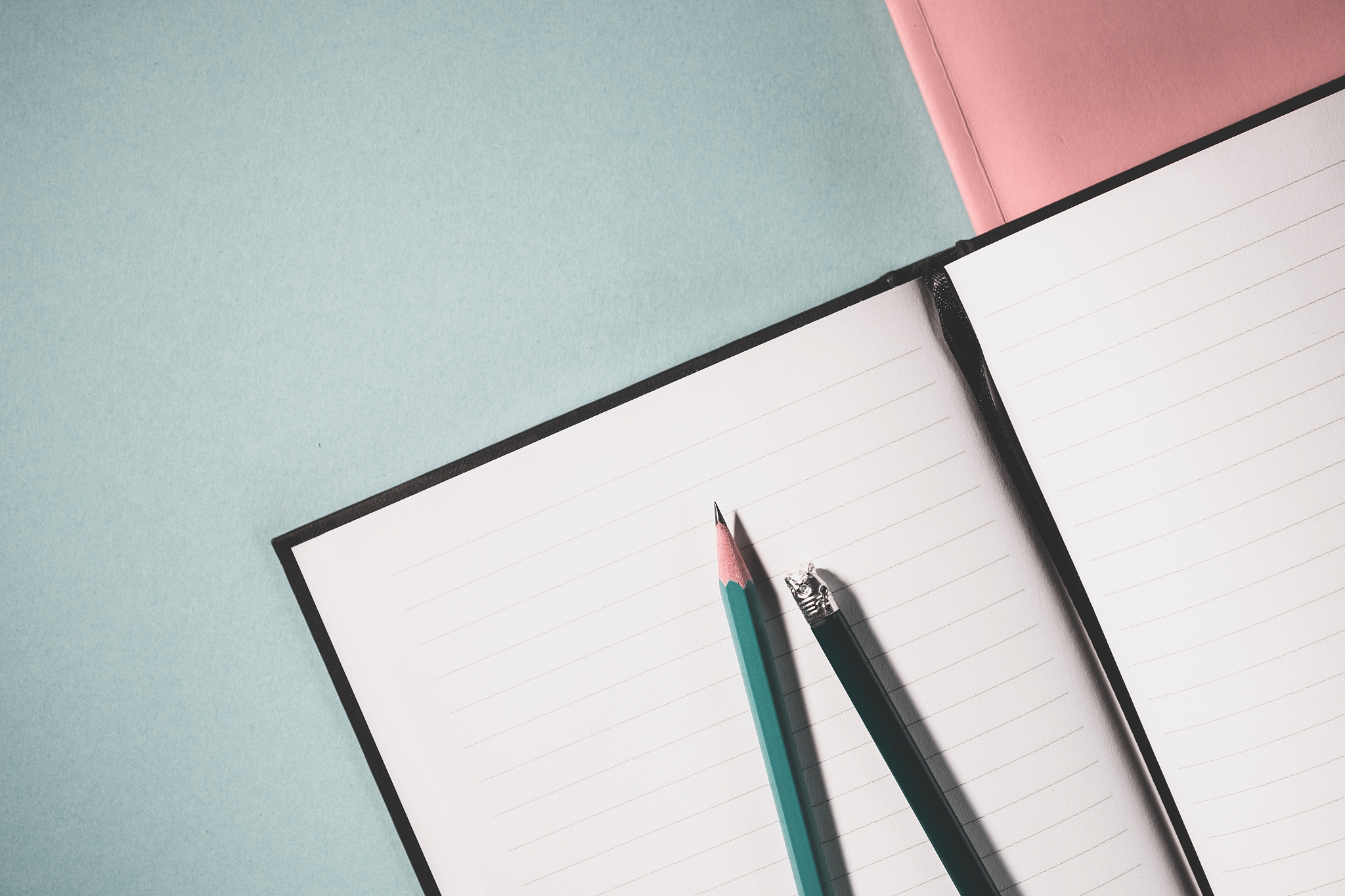 top view of school notebook on a green background, pencils and s