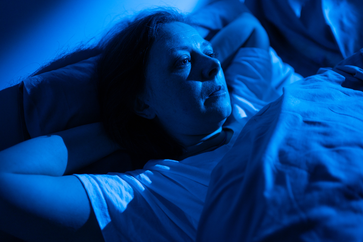 中年女子睡不着觉,眼睛睁着躺在床上,患有失眠和睡眠