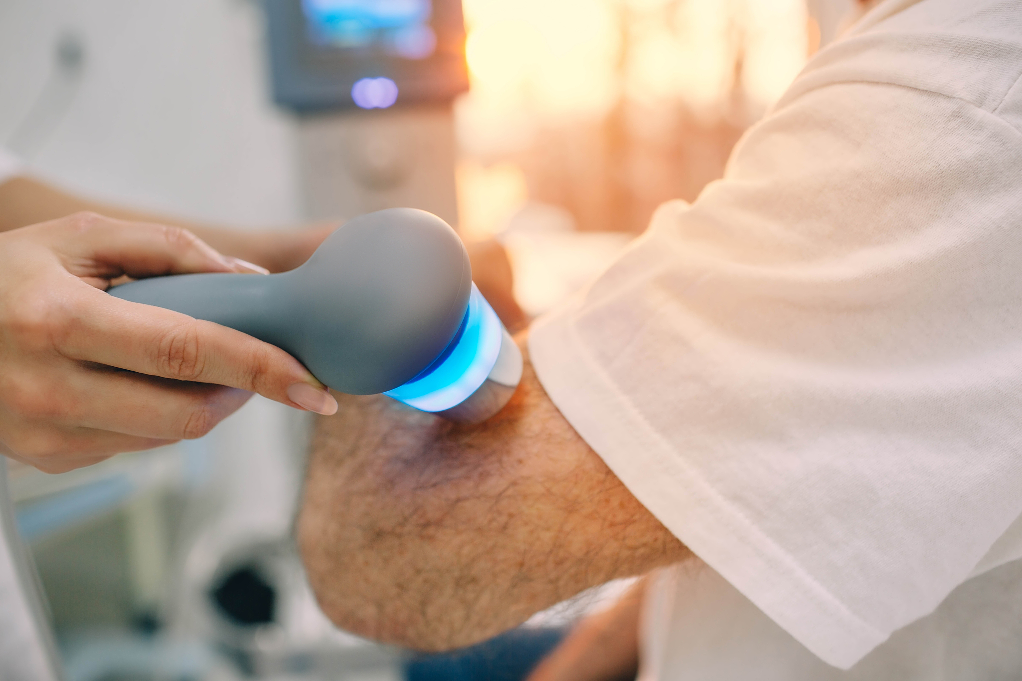 physiotherapist using ultrasound machine on hand of client in cl