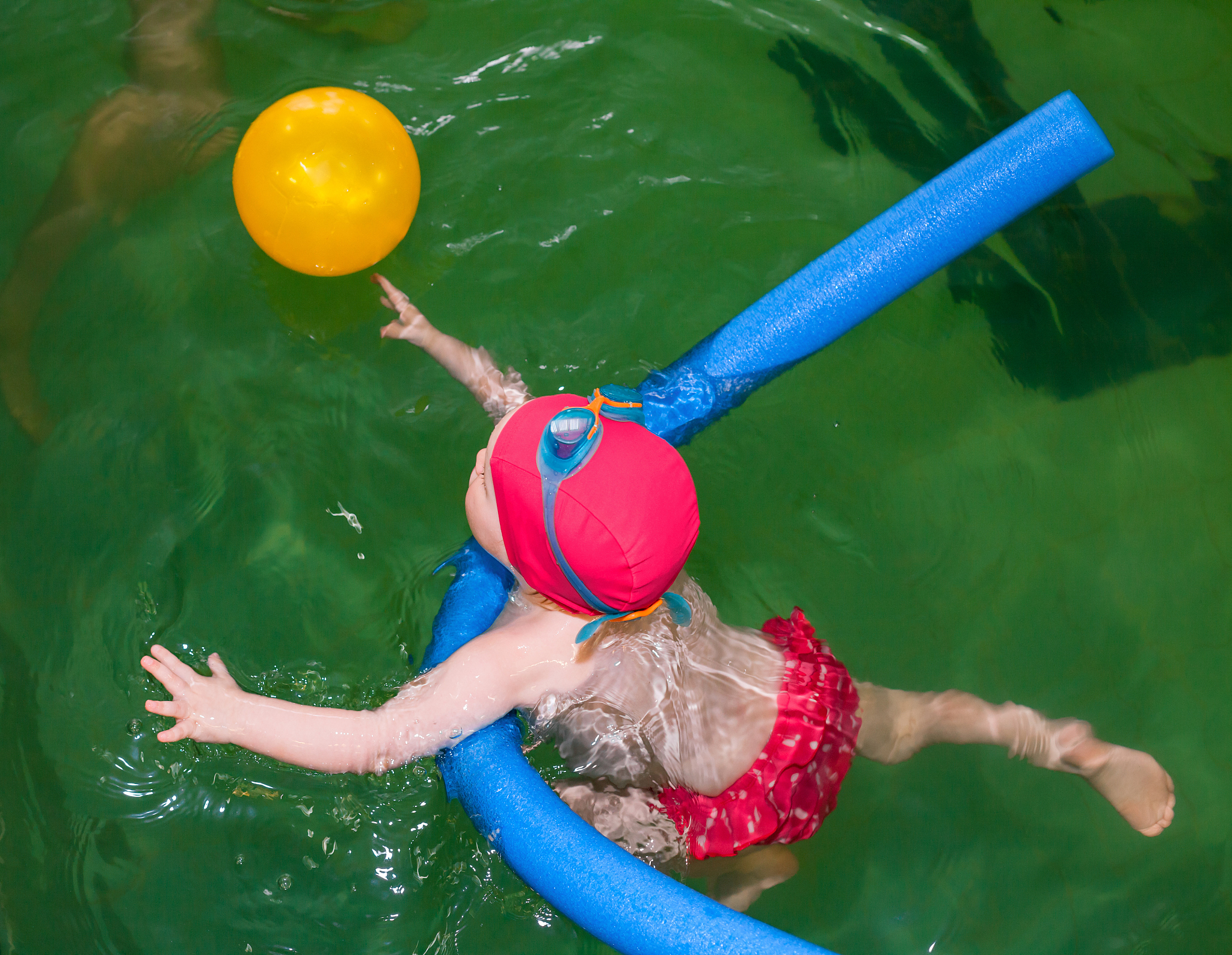 little girl learning to swim in a pool