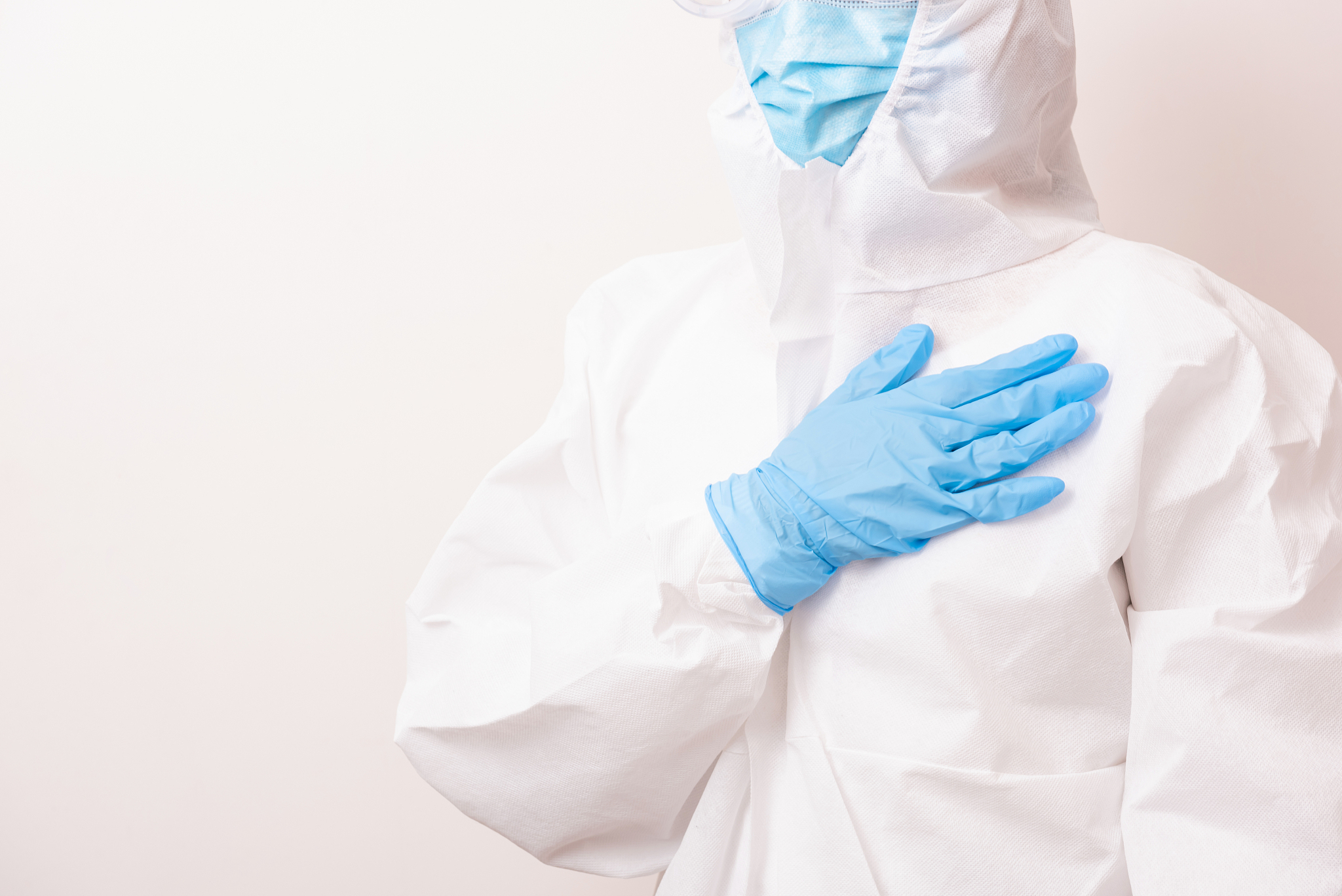 female doctor in full protective suit with hand on heart