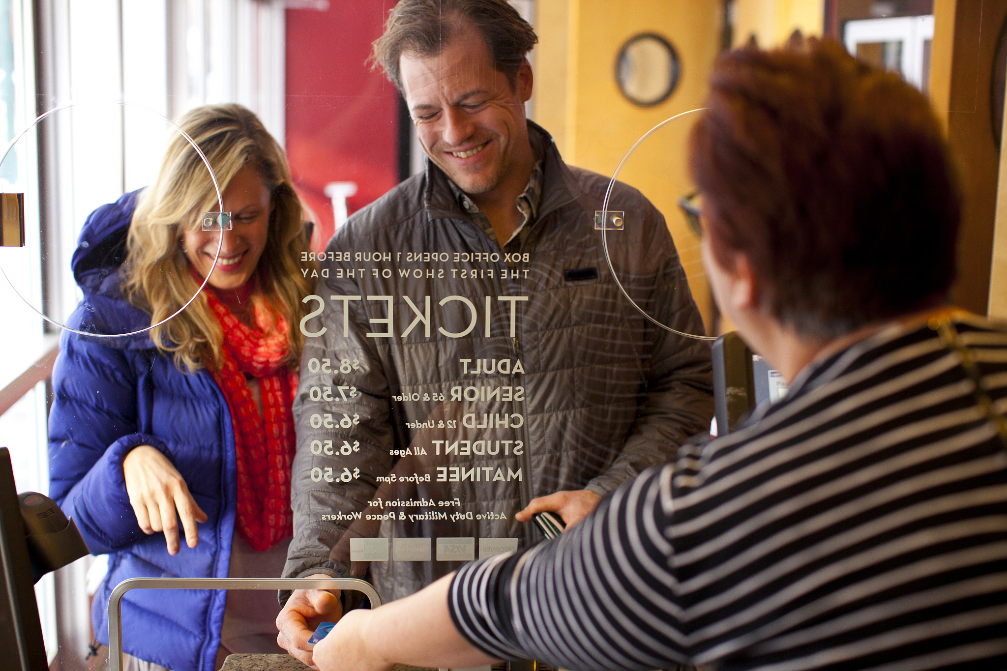 mid-adult couple buying tickets at theater box office