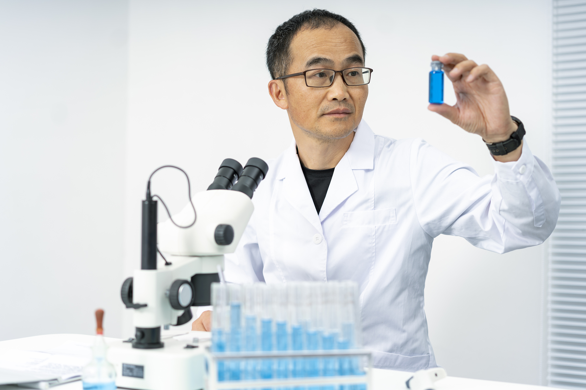 一个亚洲中年男性科学家在看试管