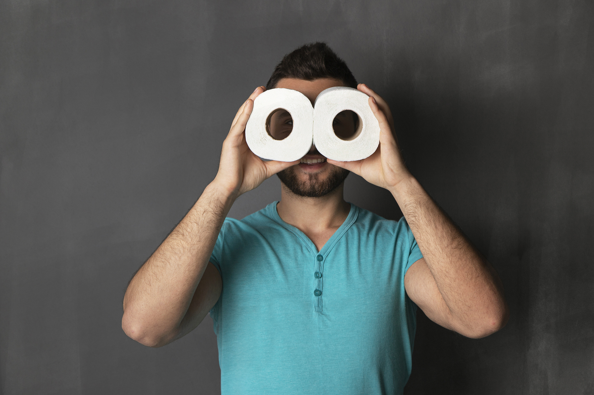 handsome guy looks through rolls of toilet paper
