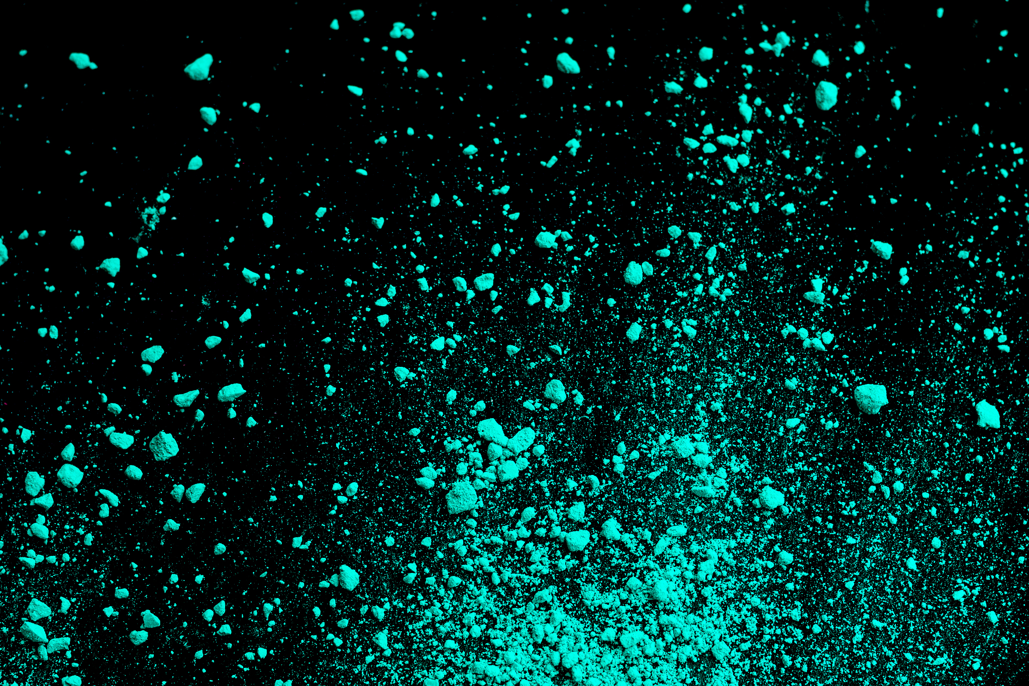 a splatter of green blue colored pigment powder on black backgro