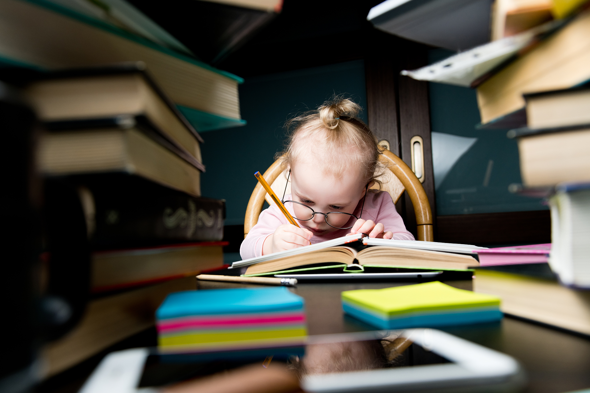 a child in large glasses painstakingly writes something in a not