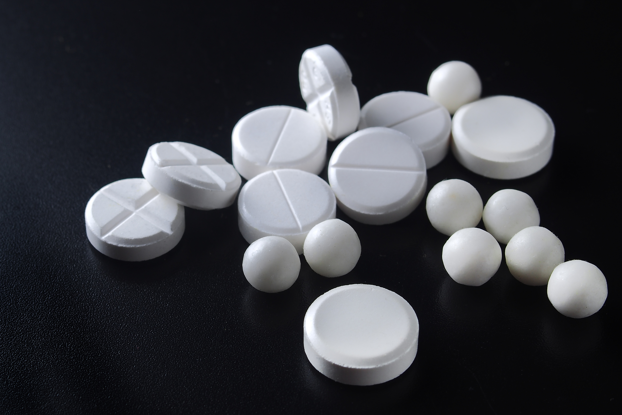 white pills of different sizes on a black background
