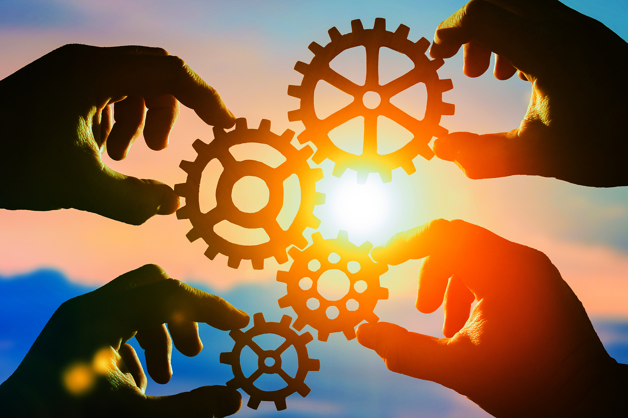 gears in the hands of people against the sky.