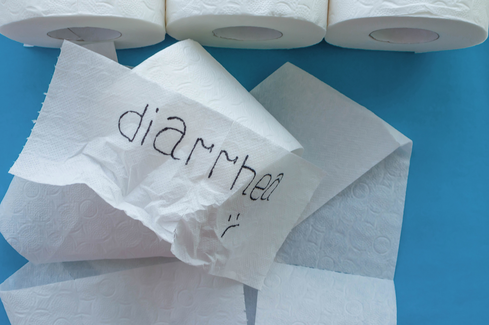 rolls of white toilet paper labeled "diarrhea" on a blue backgro