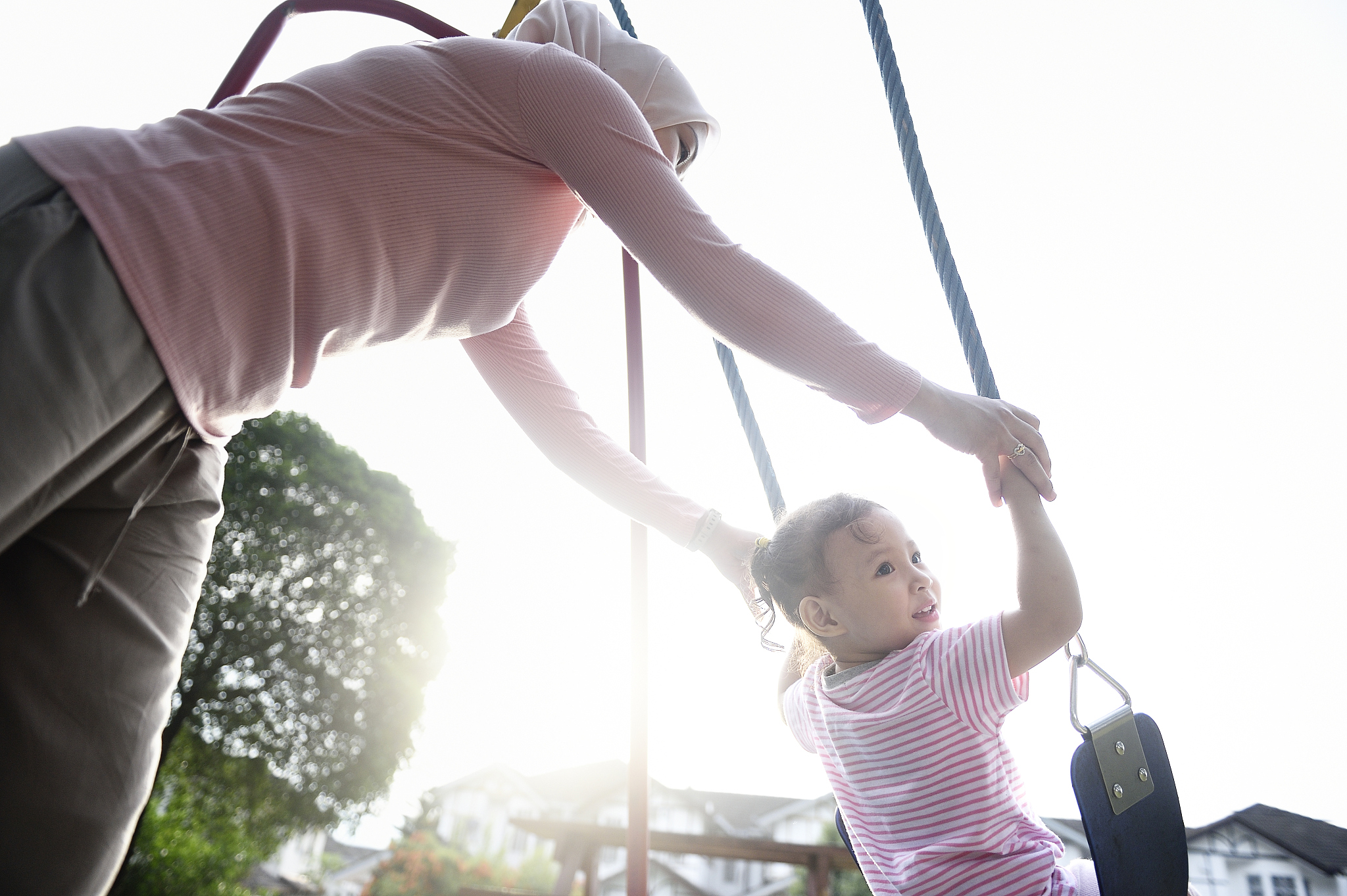 malay woman playing with her daughter on a swing at dawn