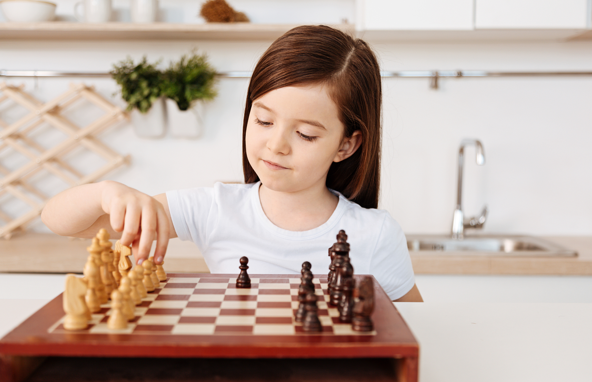 smart little girl playing chess alone