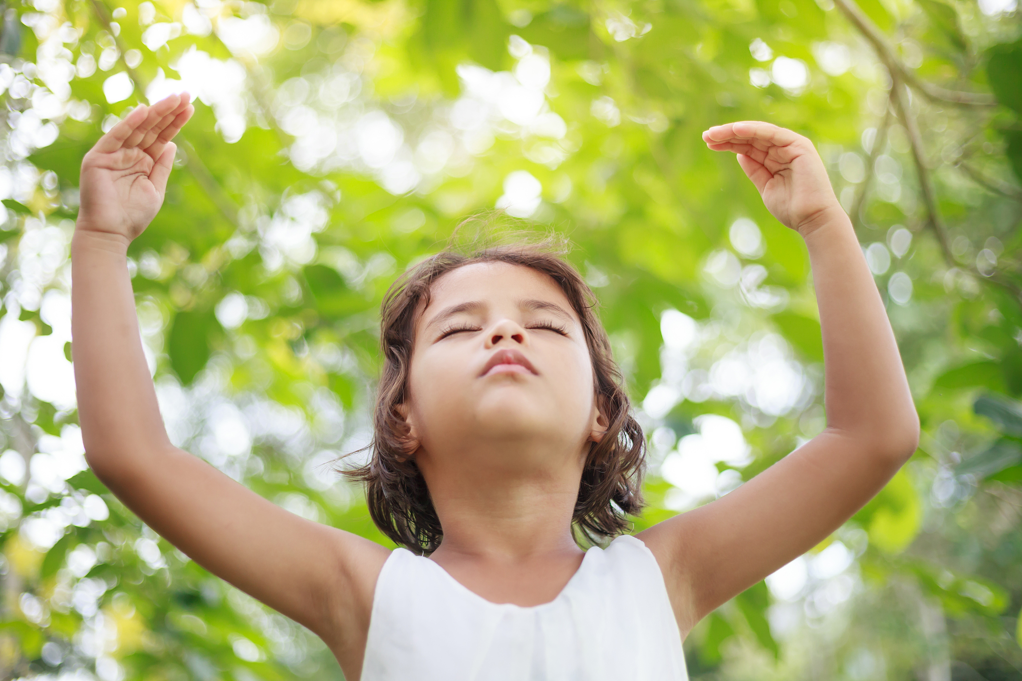 child girl raised arms in the green garden.
