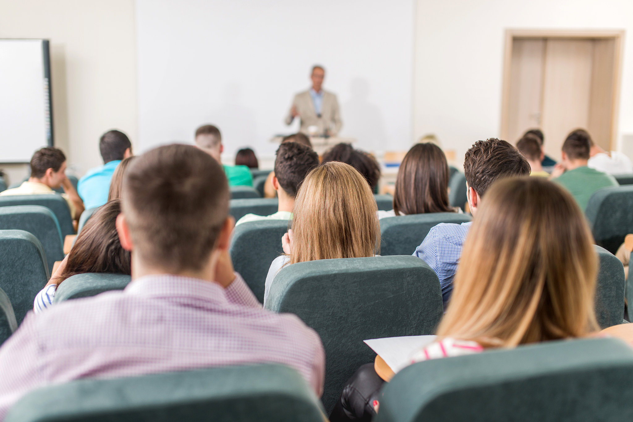 rear view of group of students in amphitheatre during lecture.
