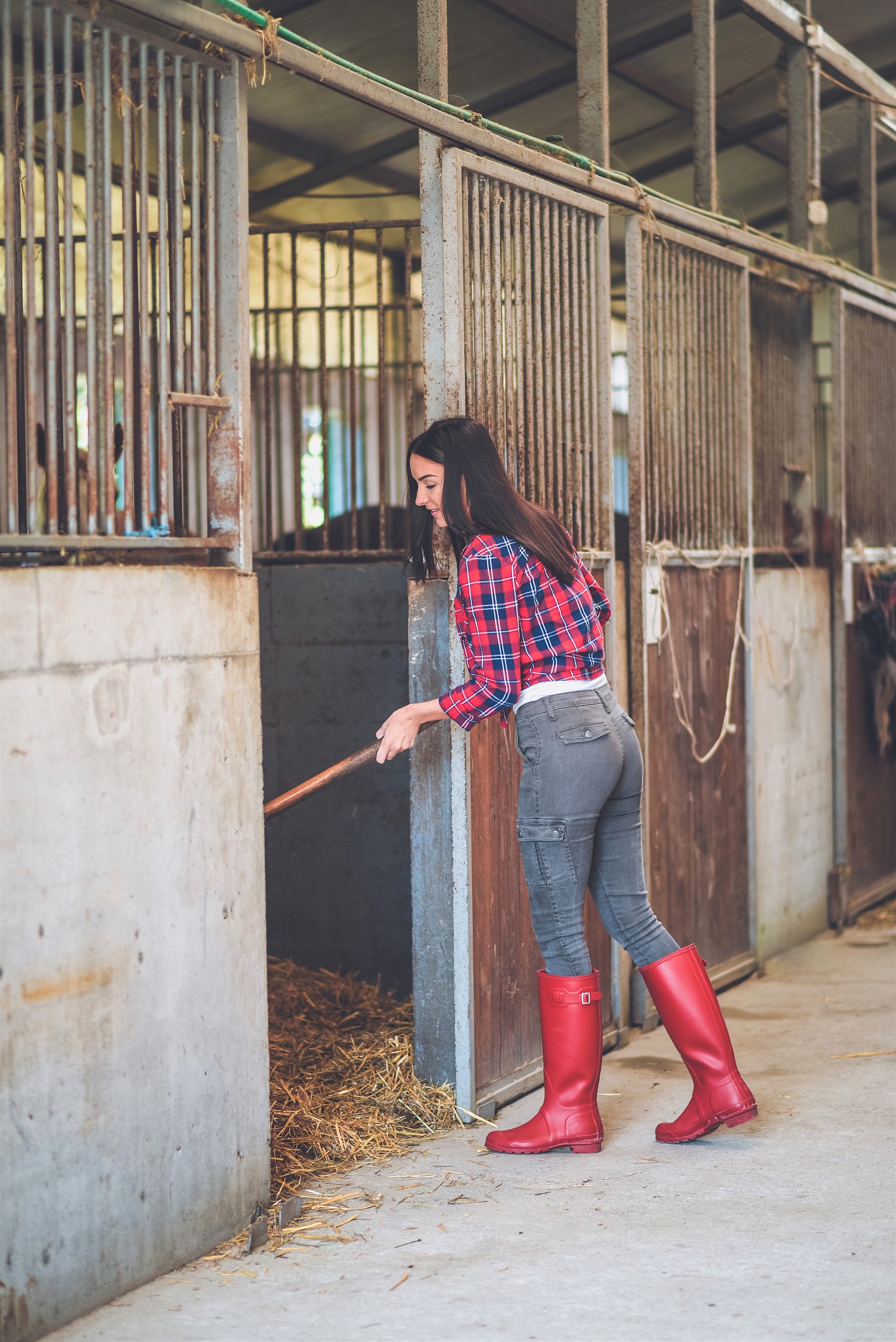 a young woman cleans stable