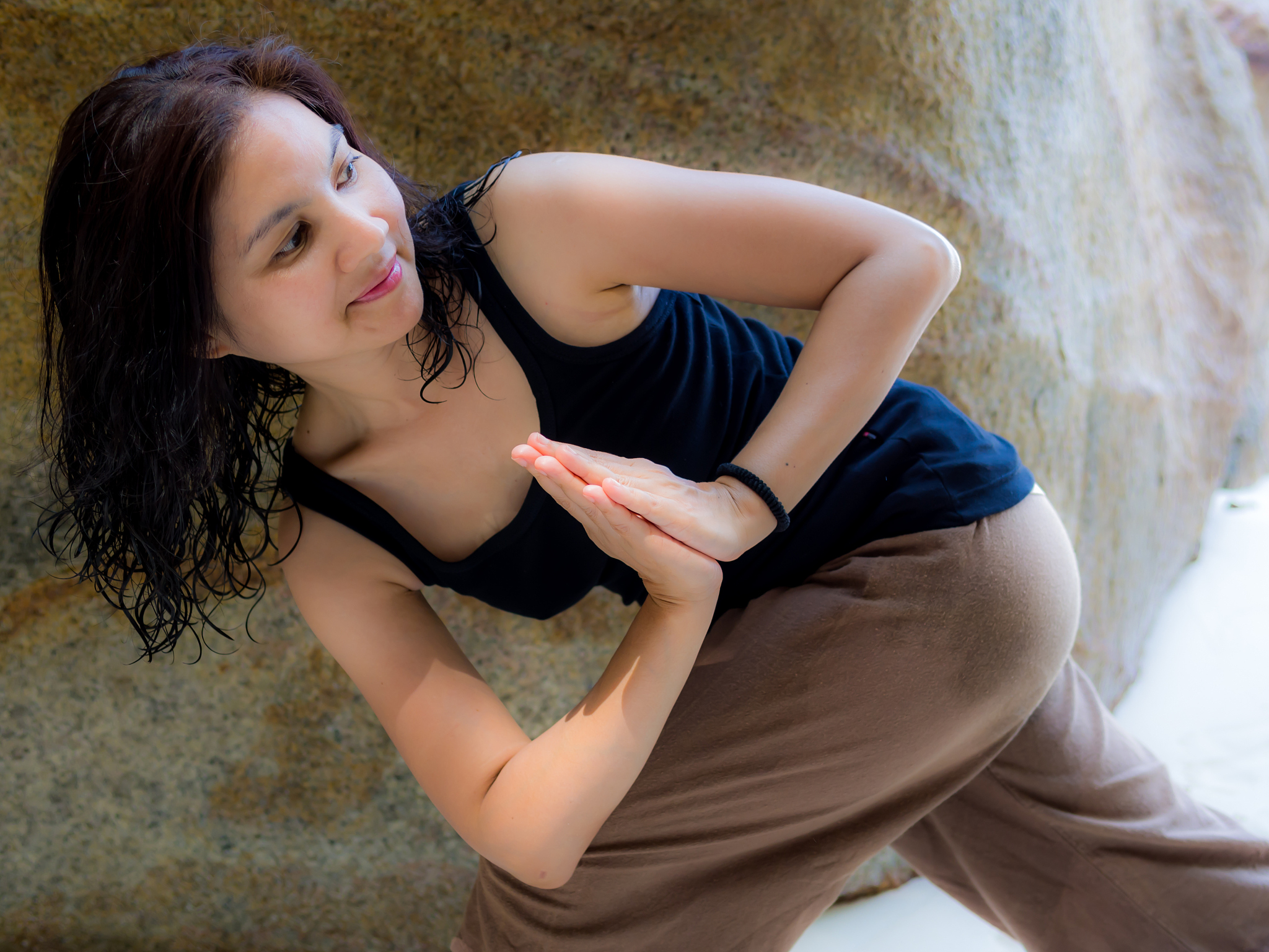 asian woman doing yoga parivrtta anjaneyasana pose at the beach