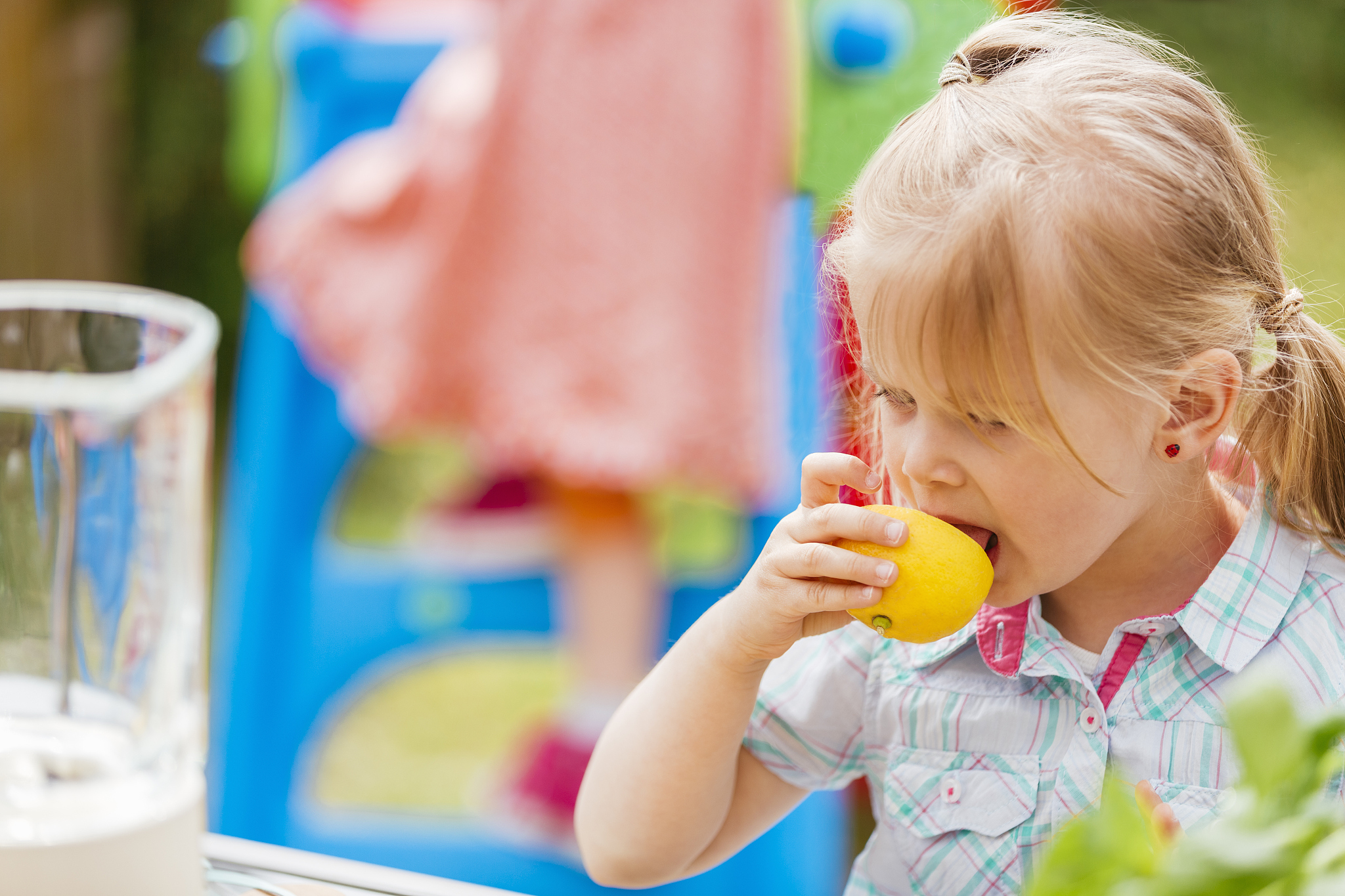cute little girl tasting fresh lemon