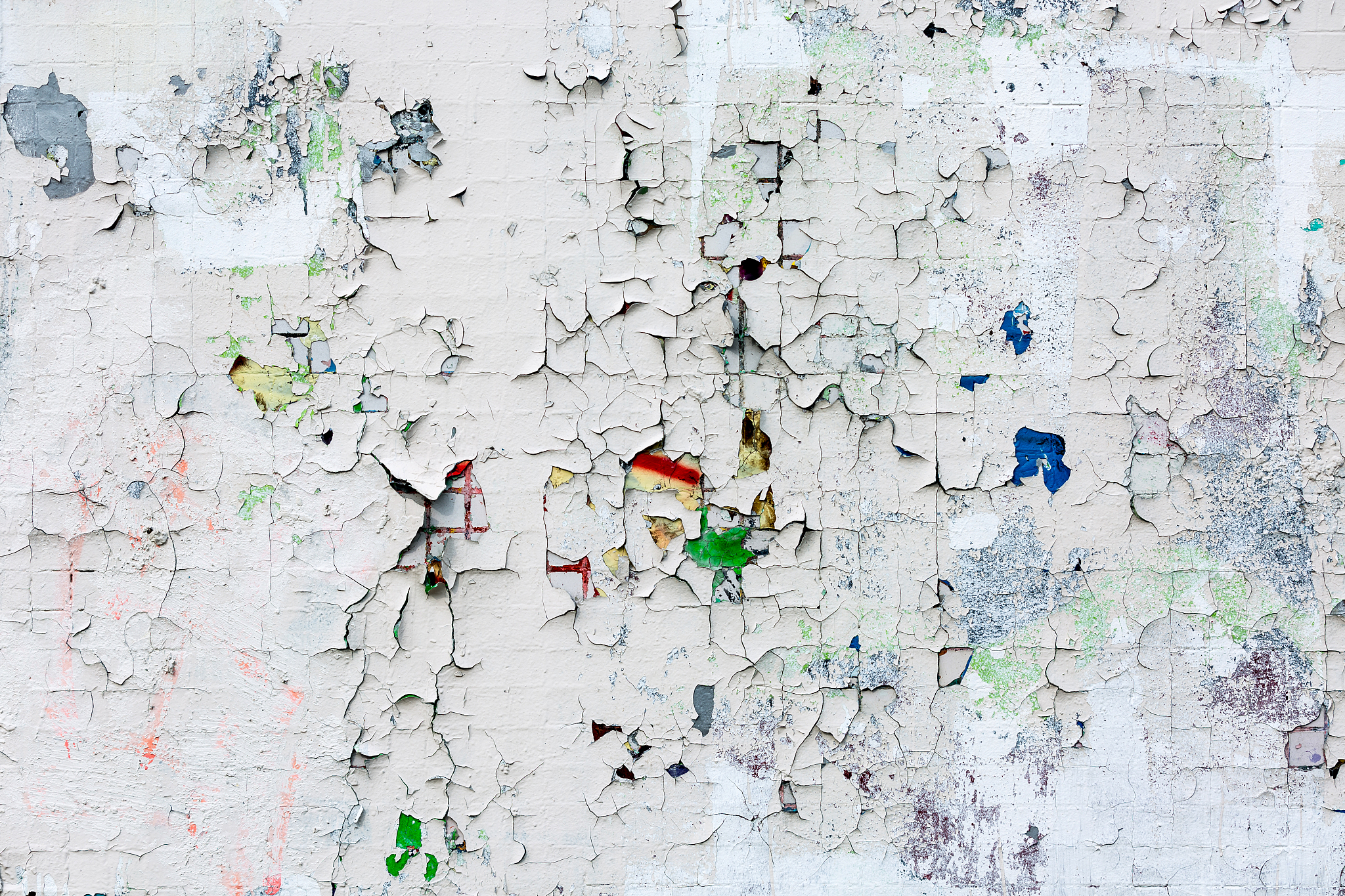 wall of small tiles in white paint with cracks.