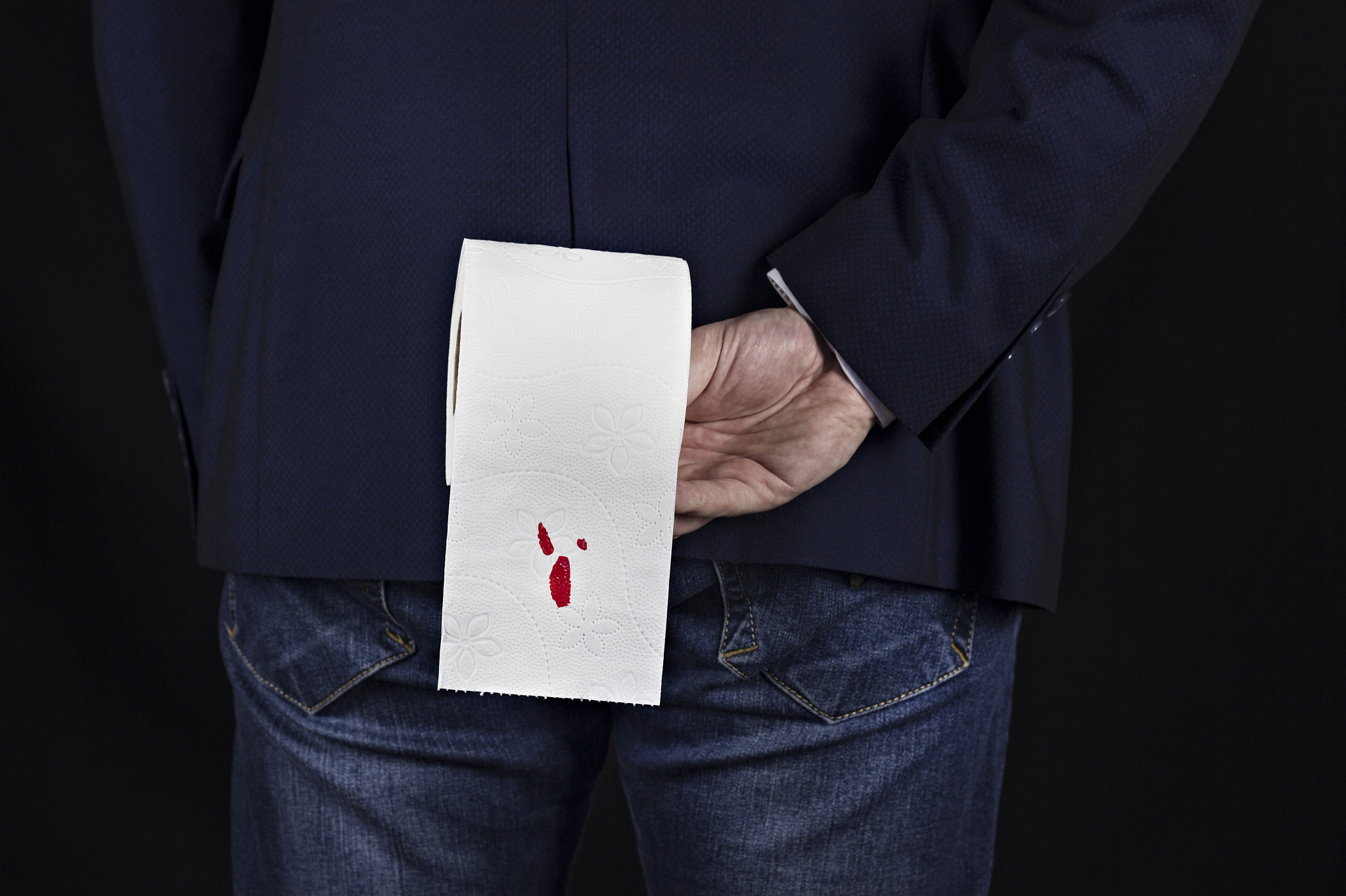 man in suit holds toilet paper with blood, hemorrhoids, black ba