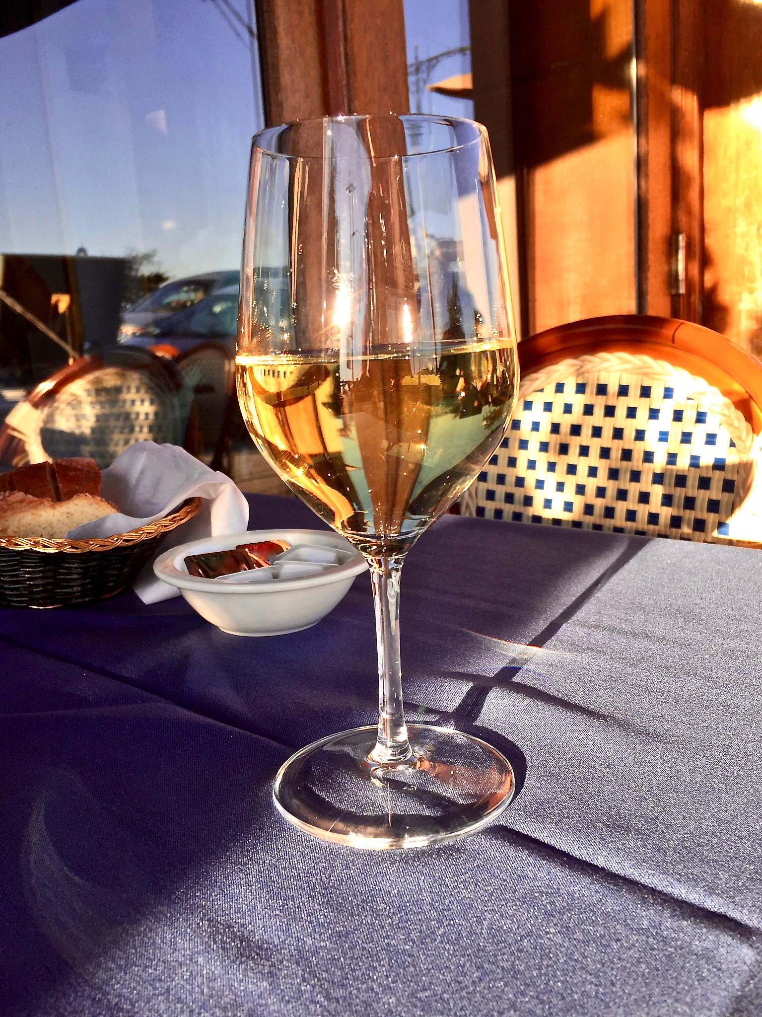 a glass of retsina wine on a table at an outdoor sidewalk restau