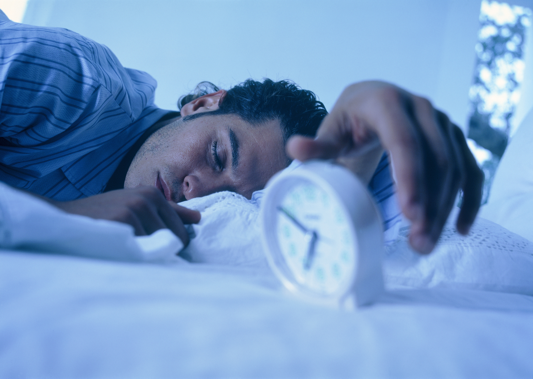 young man in bed with alarm clock