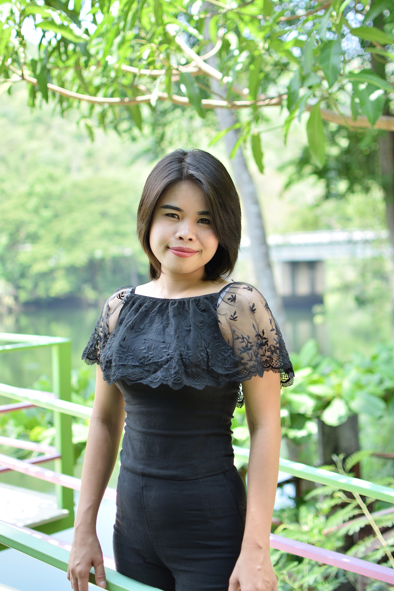 portrait of young woman with short hair standing against trees i