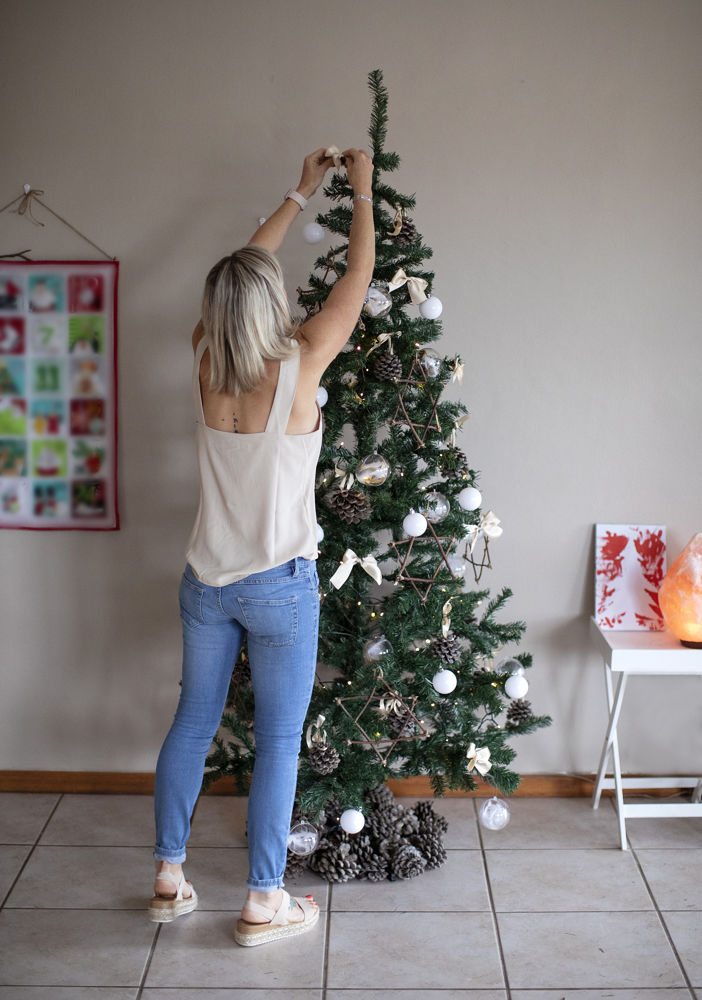 a young woman setting up a christmas tree.