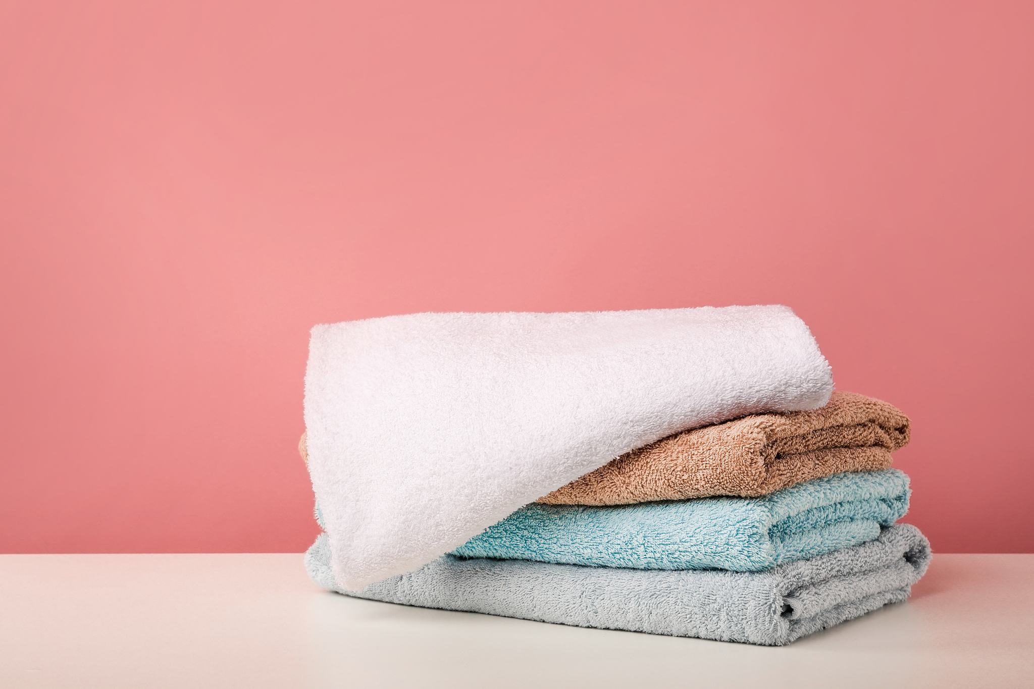 stack of bath towels on pink background