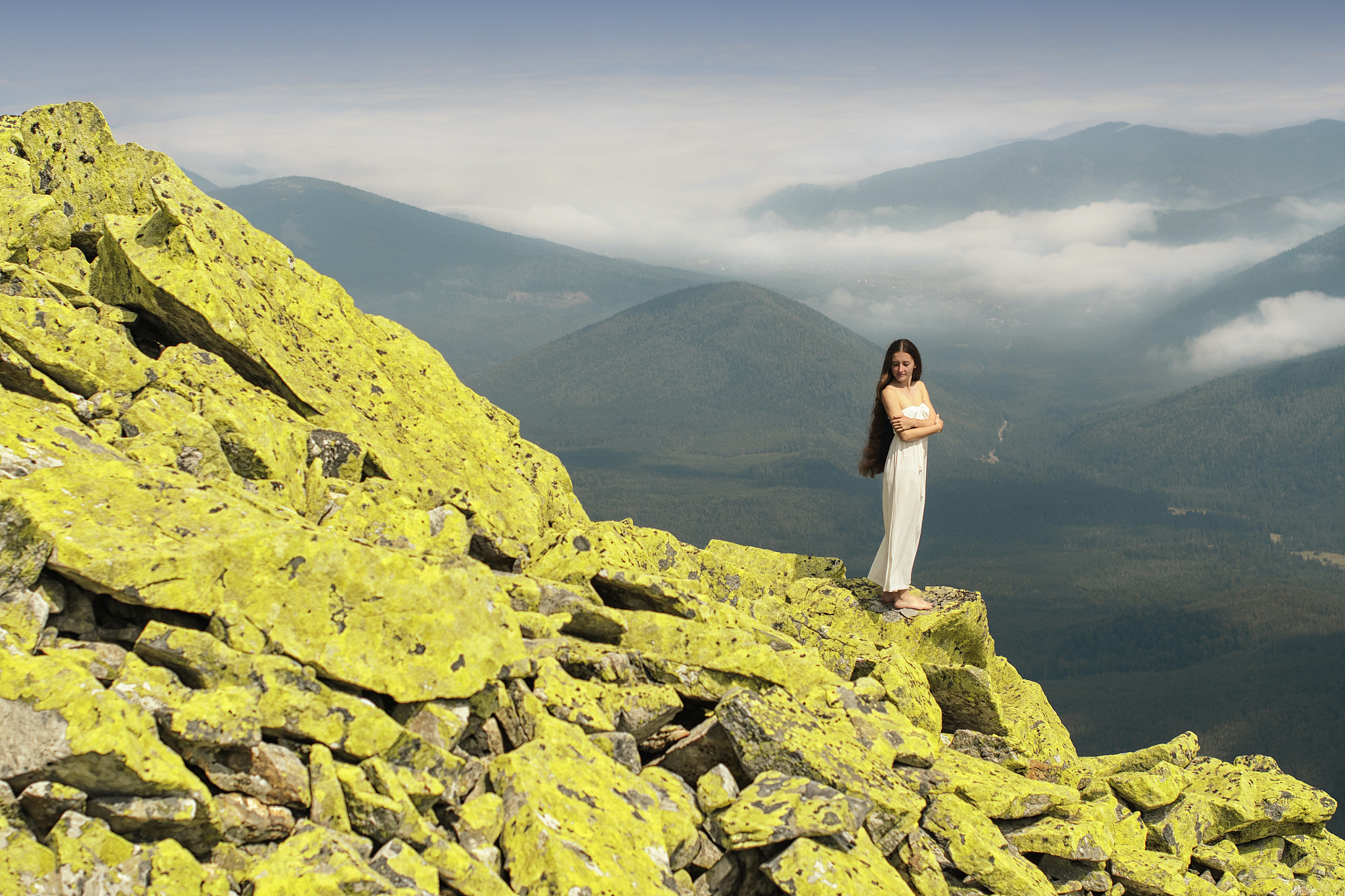 sensual young woman standing on rocks in the mountains