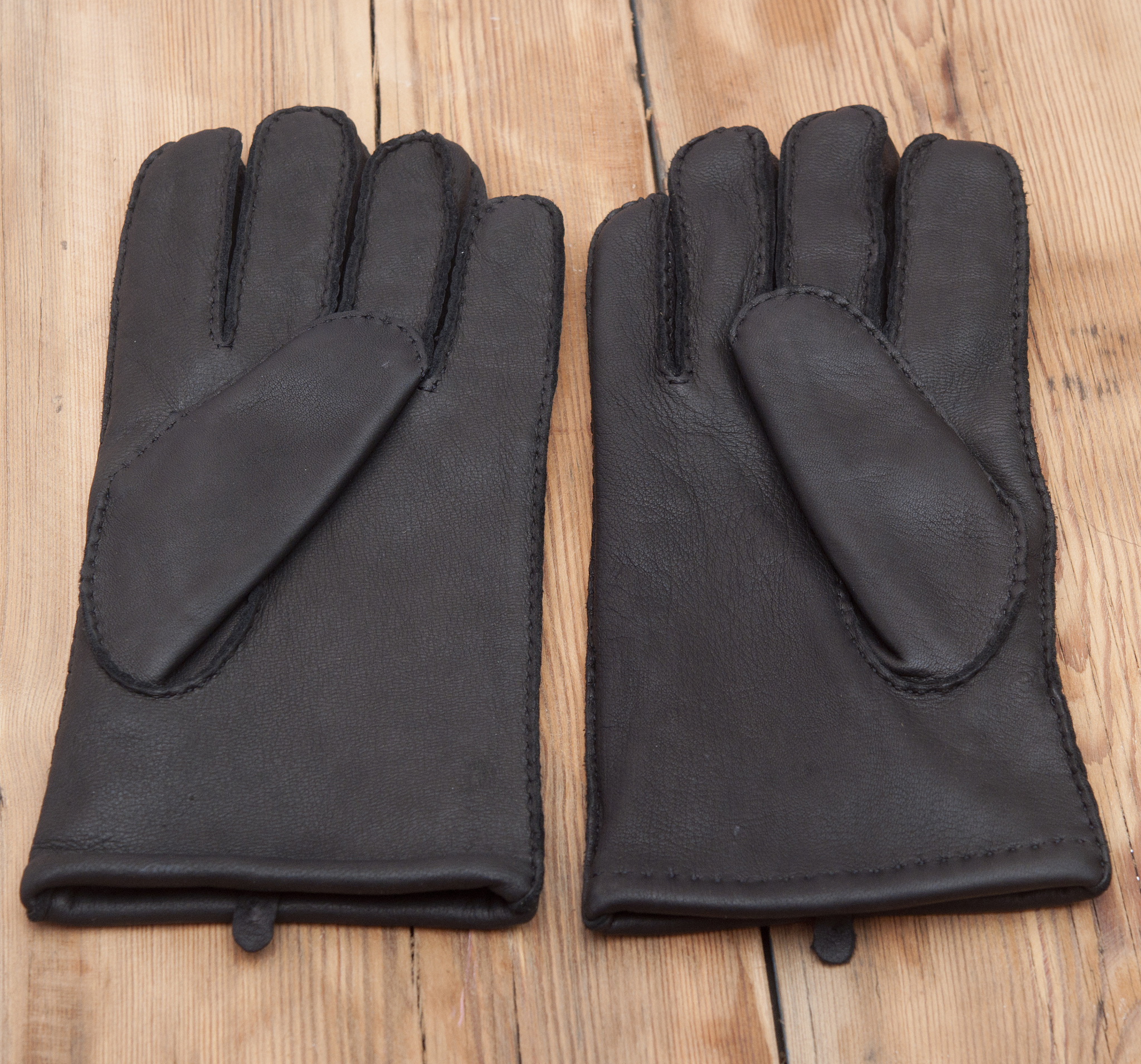 pair of men's black leather gloves on wooden table top