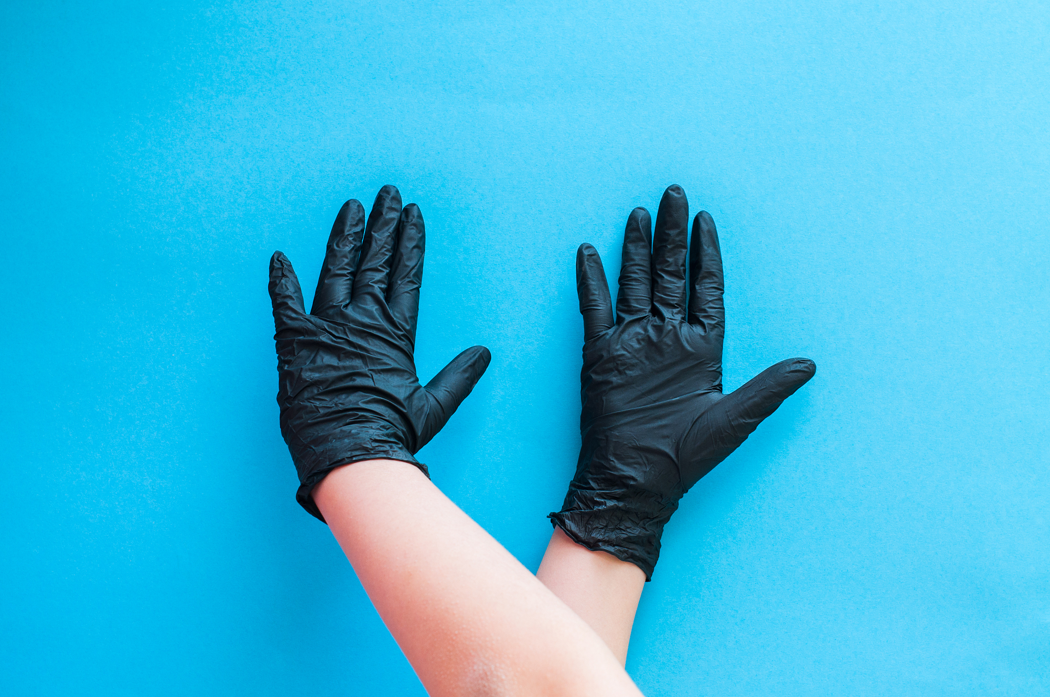hands with black gloves on blue background.
