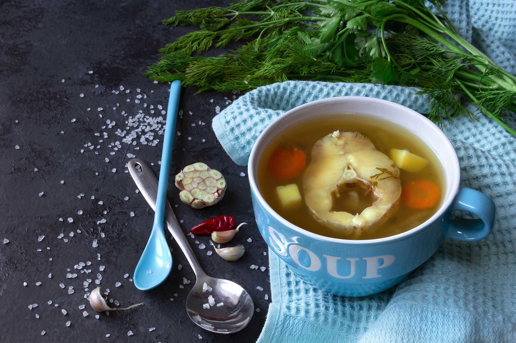 fresh fish soup in a blue bowl on a dark background. copy space.